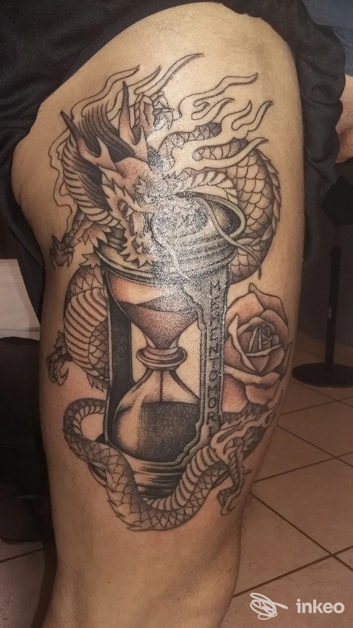 Tatuaggio su coscia: clessidra avvolta da drago e rosa. Chianti Ink, Tavarnelle Val di Pesa.