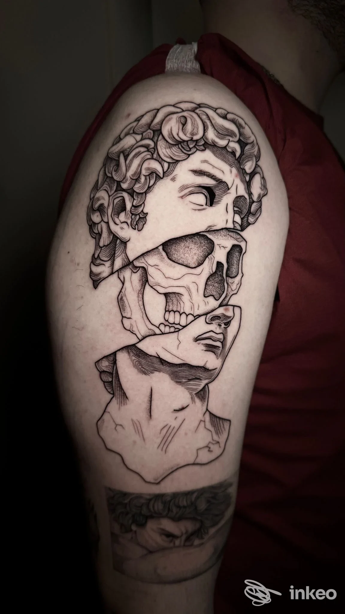 Tatuaggio in bianco e nero sul braccio superiore che combina volti e un teschio — foto per Mente Clara Tattoo Studio, Ottava Presa.
