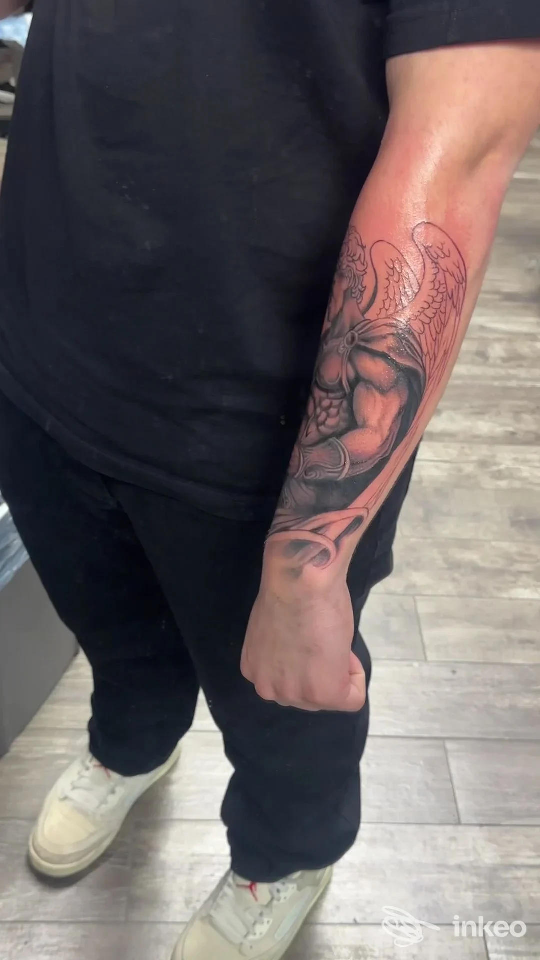 Avambraccio con tatuaggio realistico di figura alata, foto scattata al tattoo store a Napoli in ambiente di studio.