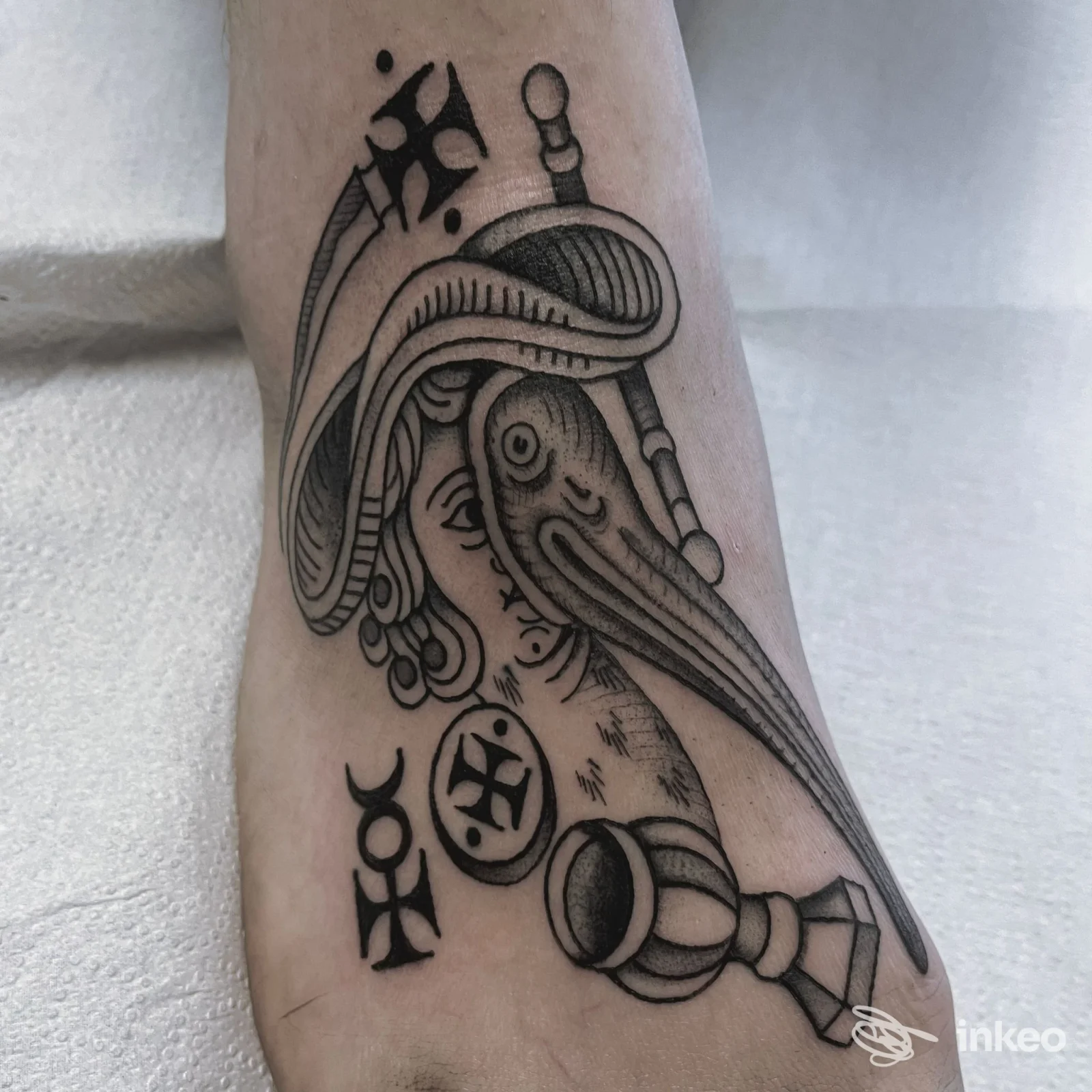 Tatuaggio in nero sul collo del piede con figura stilizzata, simboli e dettagli a tratteggio; lavoro mostrato dallo studio Buio Omega a Verona.