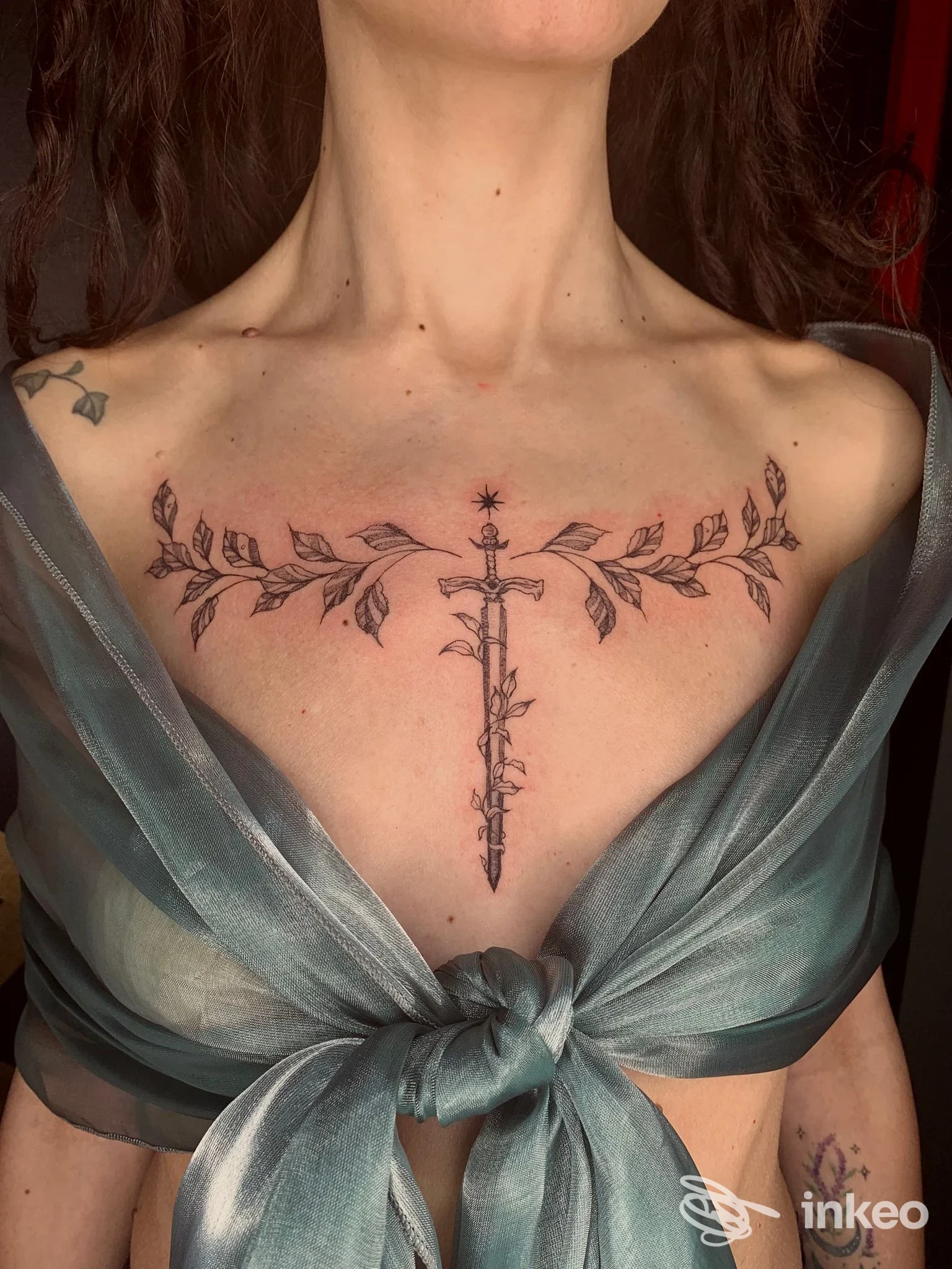 Tatuaggio ornamentale al petto con pugnale verticale e rami orizzontali, scatto di Athanor Tattoo Studio, Verona.