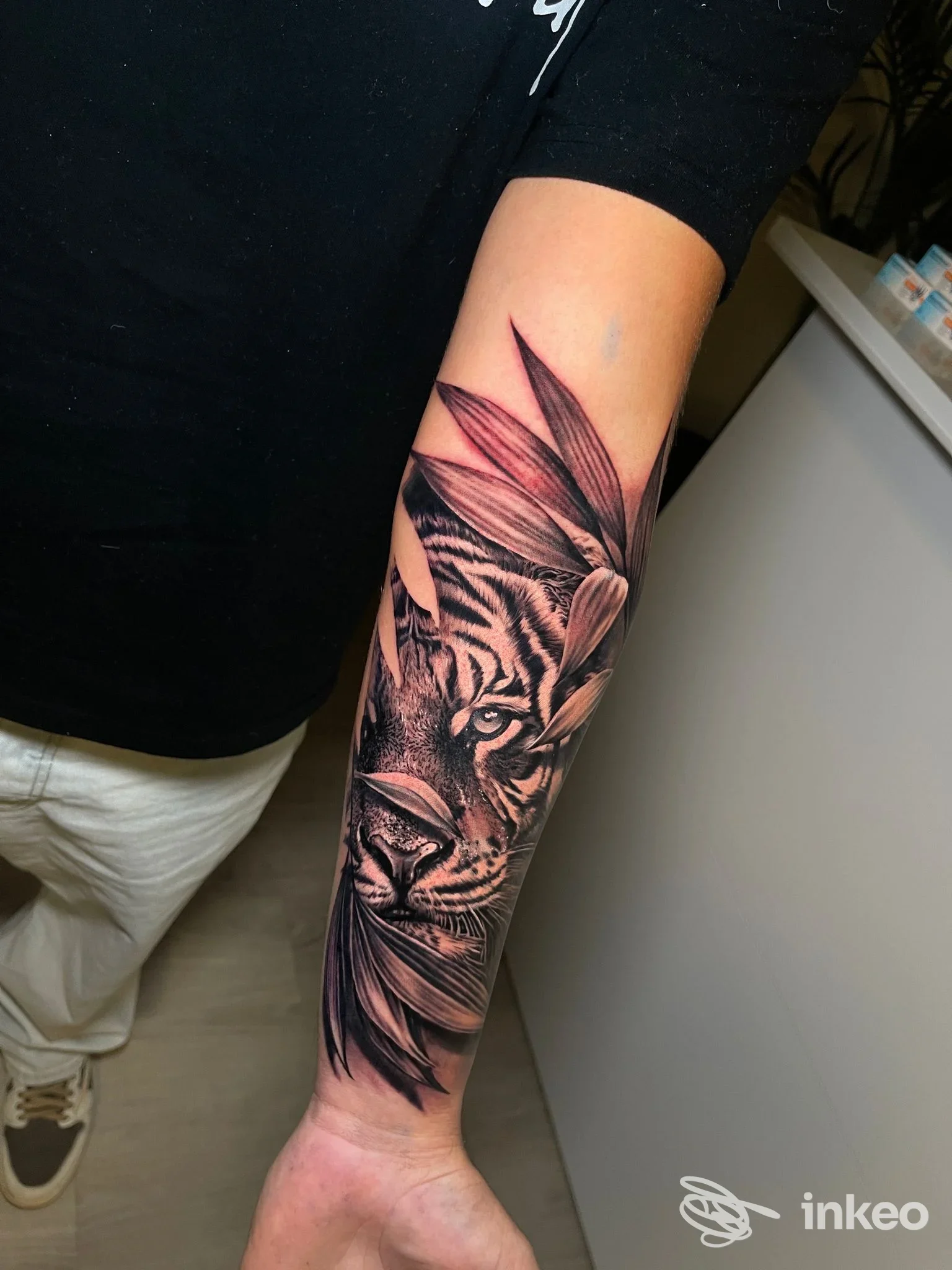 Tatuaggio realistico di tigre in bianco e nero sul braccio, realizzato sulla pelle, con dettagli delle strisce e delle zampette.