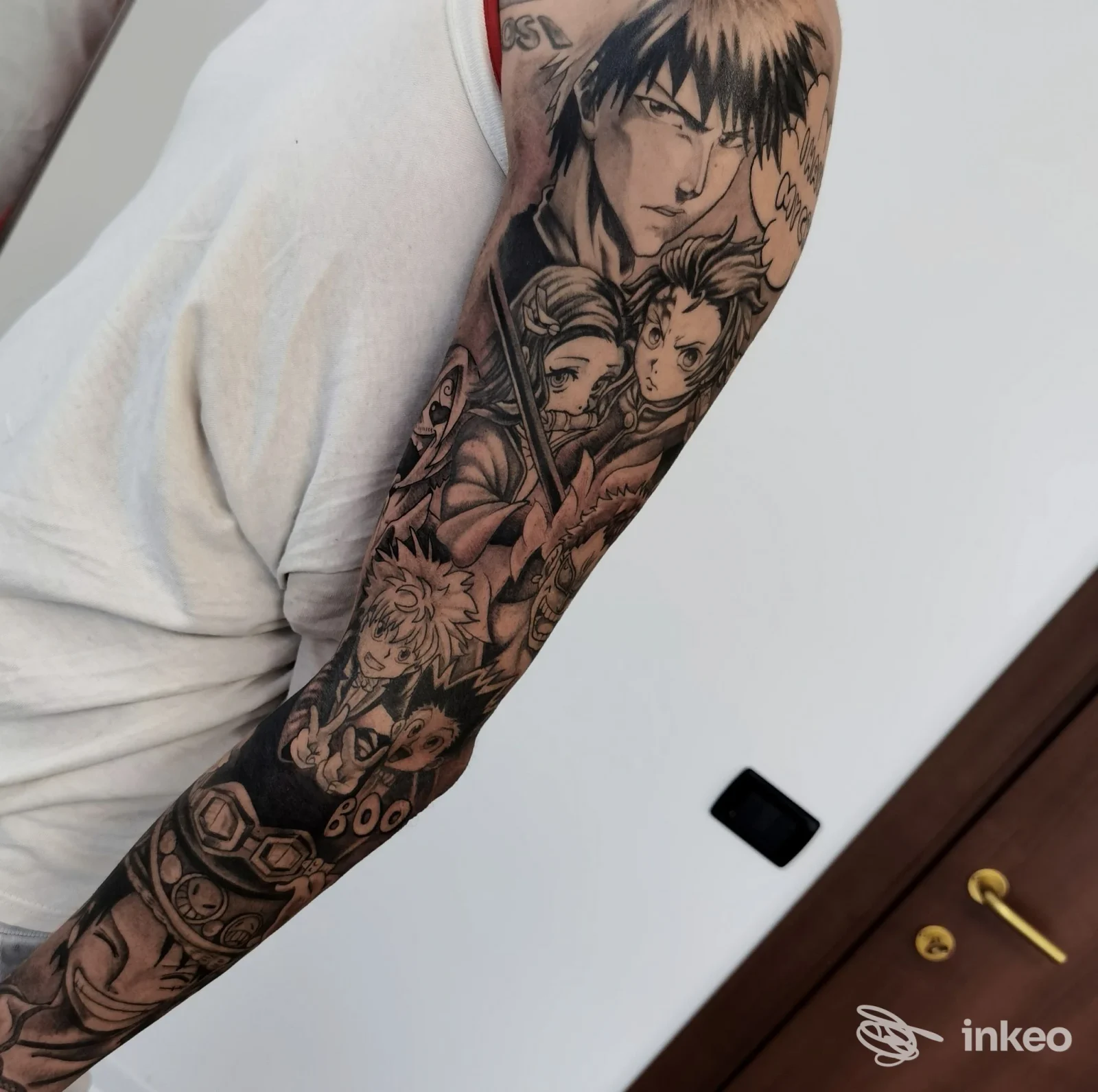 Braccio sinistro con ampio tatuaggio a tema manga, visibile dall’interno; nessun volto presente, scatto che mostra chiaramente l’opera sulla pelle.