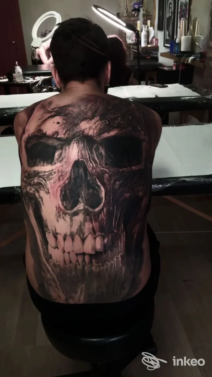 Tattoo realistico a tema teschio occupante la schiena di una persona, scuro e dettagliato, all’interno di uno studio di tatuaggi chiamato Black Island Tattoo.