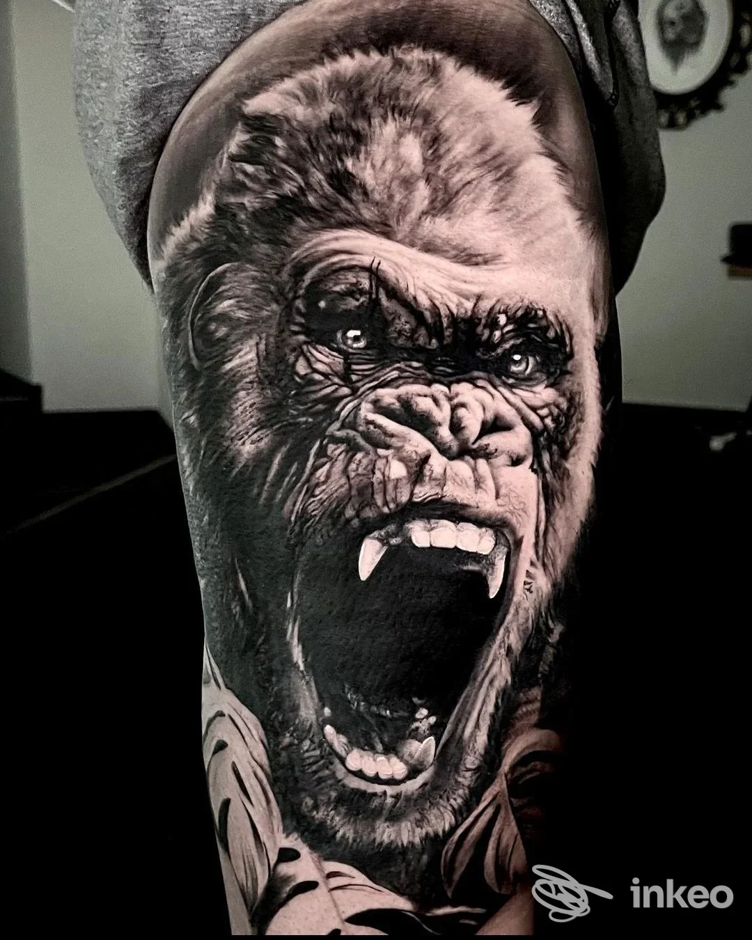 Tattoo realistico in bianco e nero di una testa di gorilla aperta in un'espressione ruggente, situato sulla parte esterna del braccio, su pelle reale, senza elementi di interfaccia sociale.