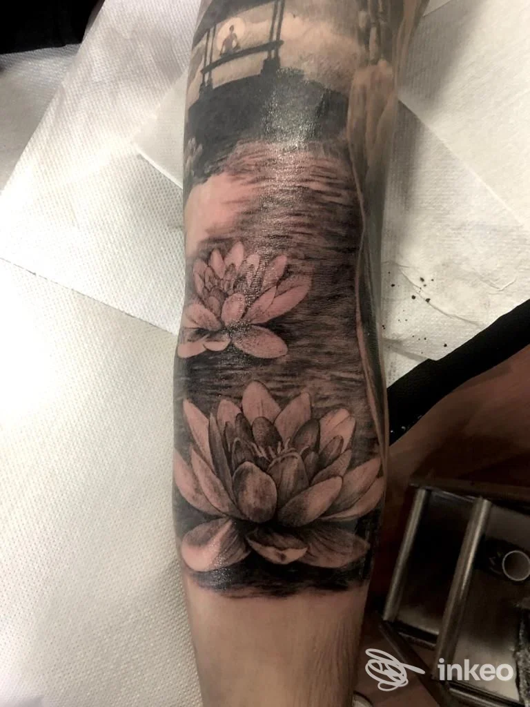 Tattoo sul braccio raffigurante fiori di loto realizzato sulla pelle, eseguito dallo studio Your Round Tattoo Studio, in bianco e nero.