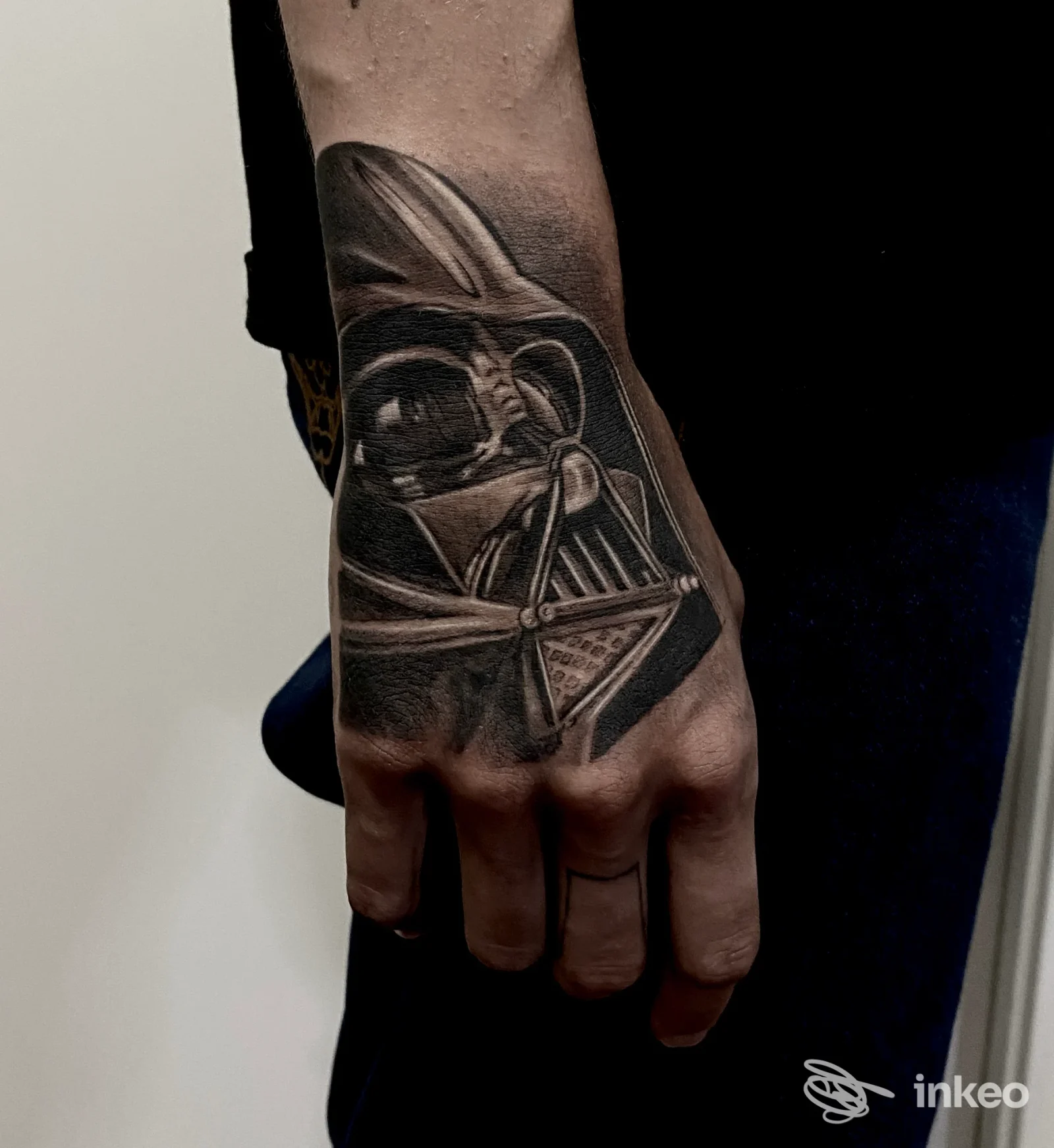 Braccio sinistro con tatuaggio realistico di Darth Vader, tonalità nere; la pelle è reale, visibile sull’avambraccio, senza volto nell’inquadratura.