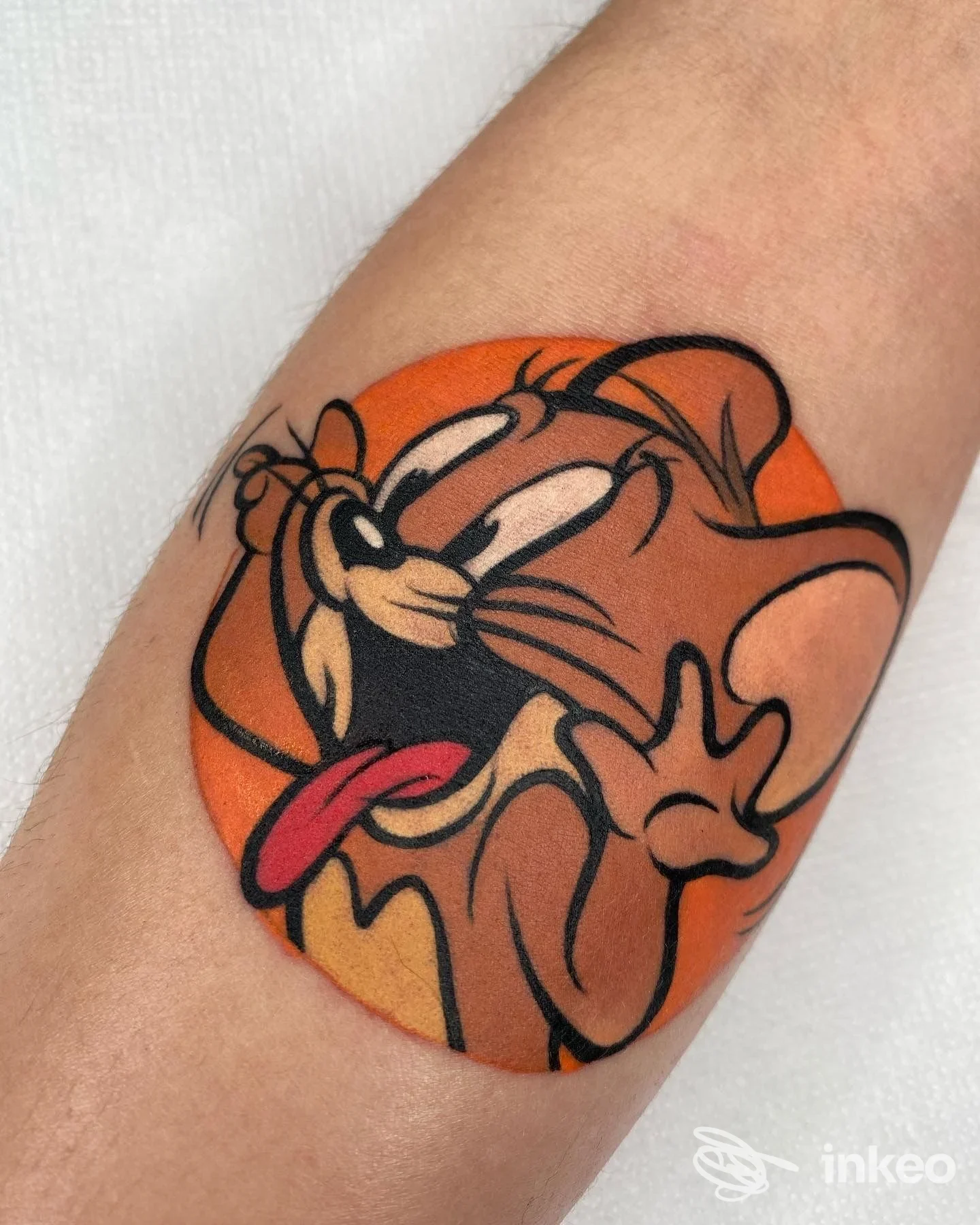 Tattoo corporeo sull'avambraccio raffigurante Pluto con sfondo arancione, linee nette e colori pieni.