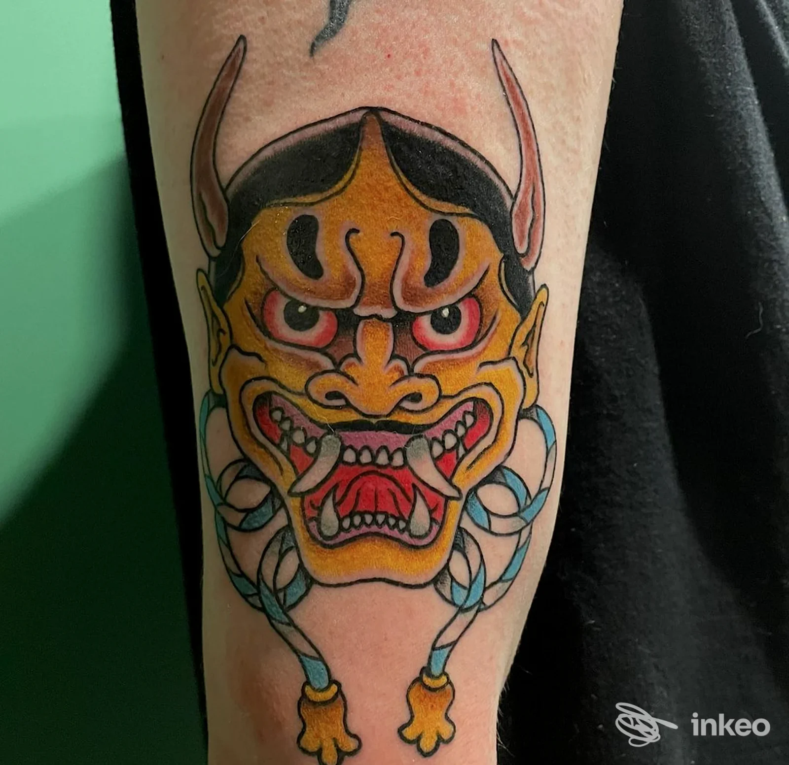 Tattoo sull'avambraccio raffigurante una maschera giapponese colorata in stile Hannya, realizzata sulla pelle. Studio River Side Klan Tattoo.