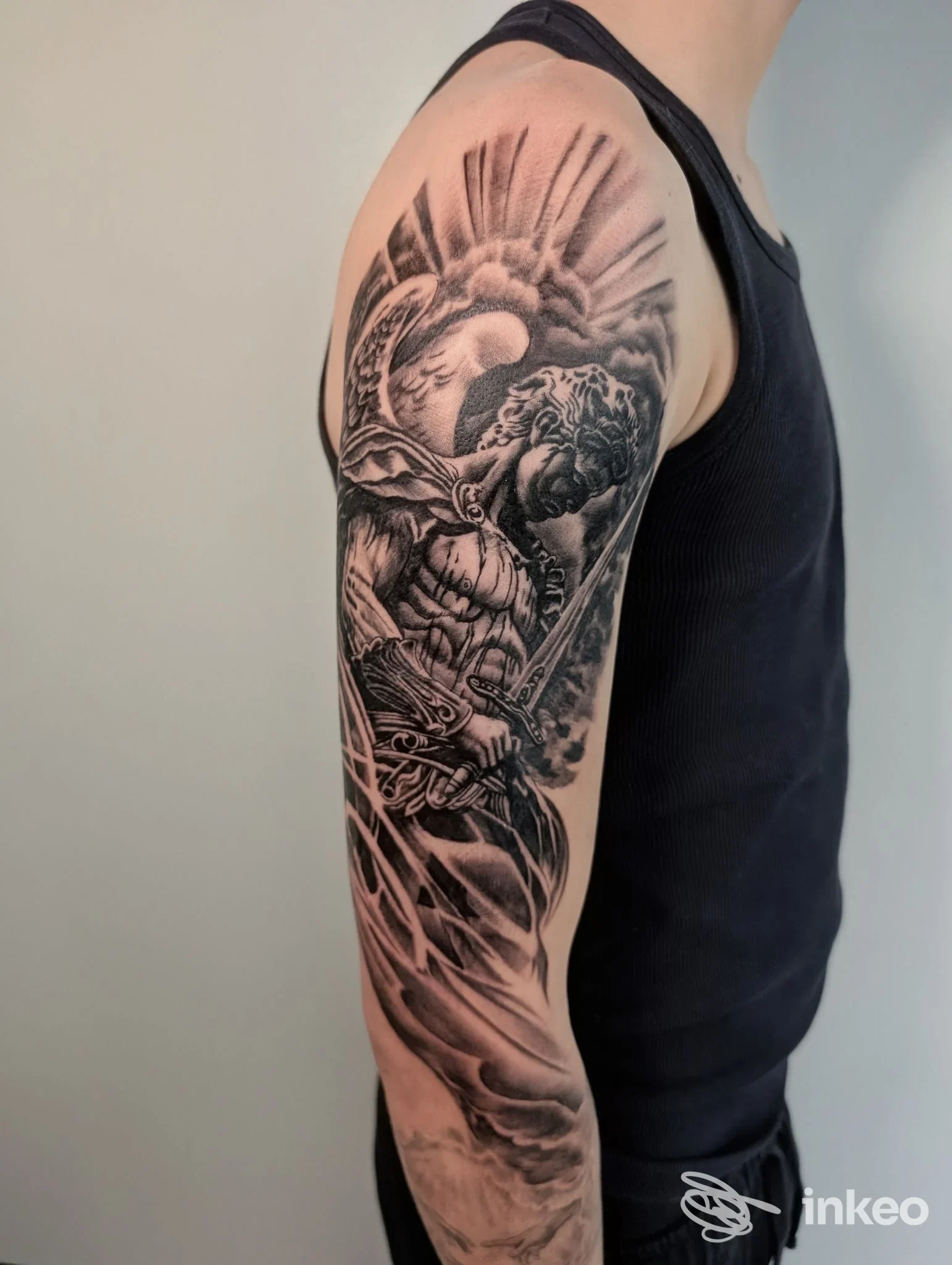 Tatuaggio in bianco e nero sul braccio di una persona, raffigurante un guerriero con scudo e spada, con sfumature e dettagli incisivi.