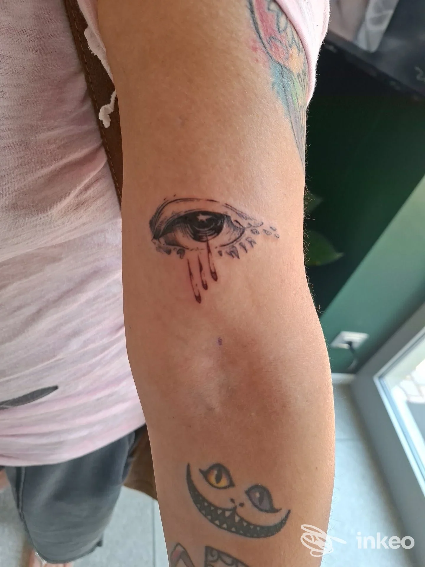 Foto di un braccio con tatuaggio raffigurante un occhio stilizzato con lacrime e una luna sorridente sotto, realizzato sul braccio. lo studio Blackout Tattoo Studio a Treviglio.
