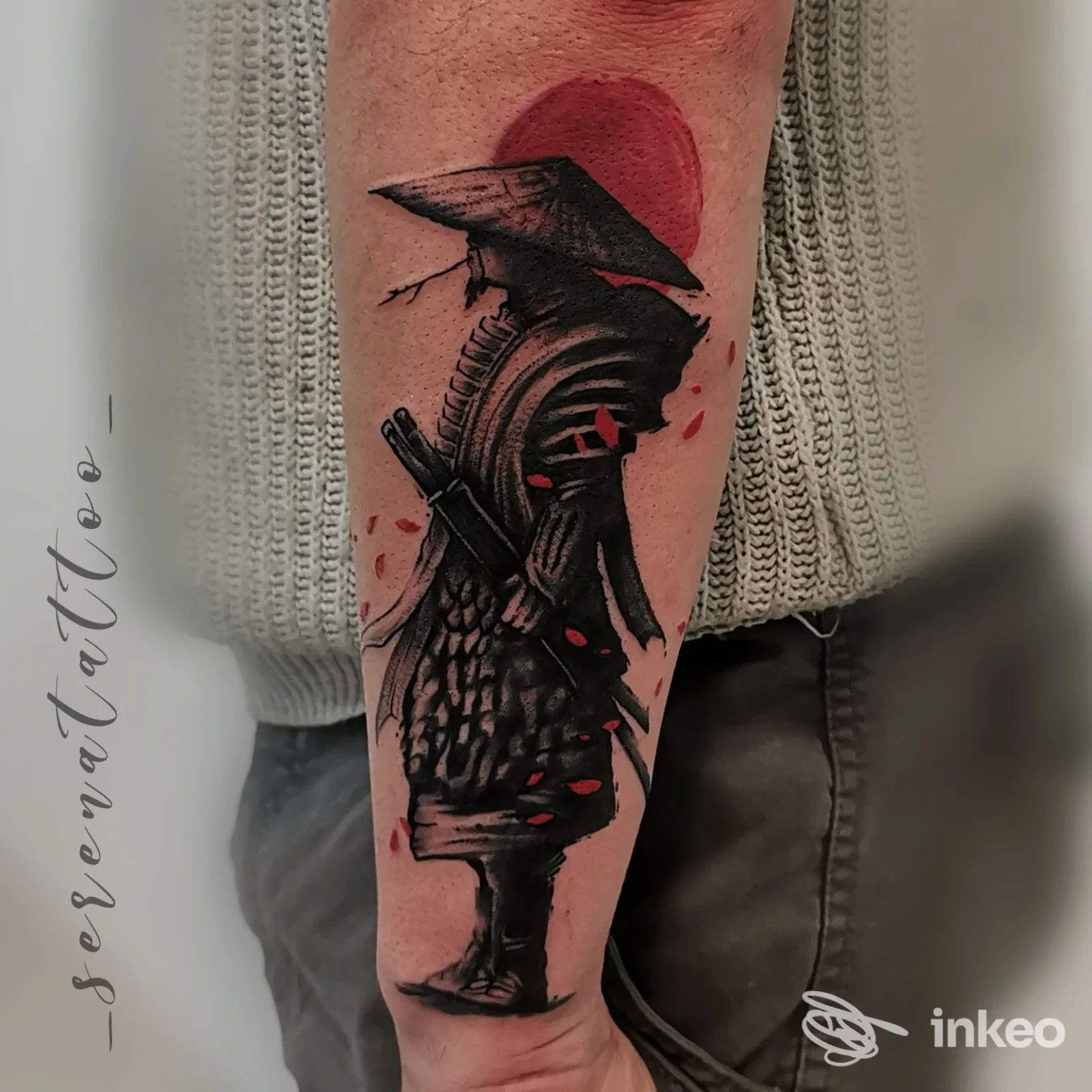 Tattoo visibile sull’avambraccio raffigurante figura in armatura con sfondo rosso, scatto ravvicinato su pelle reale.