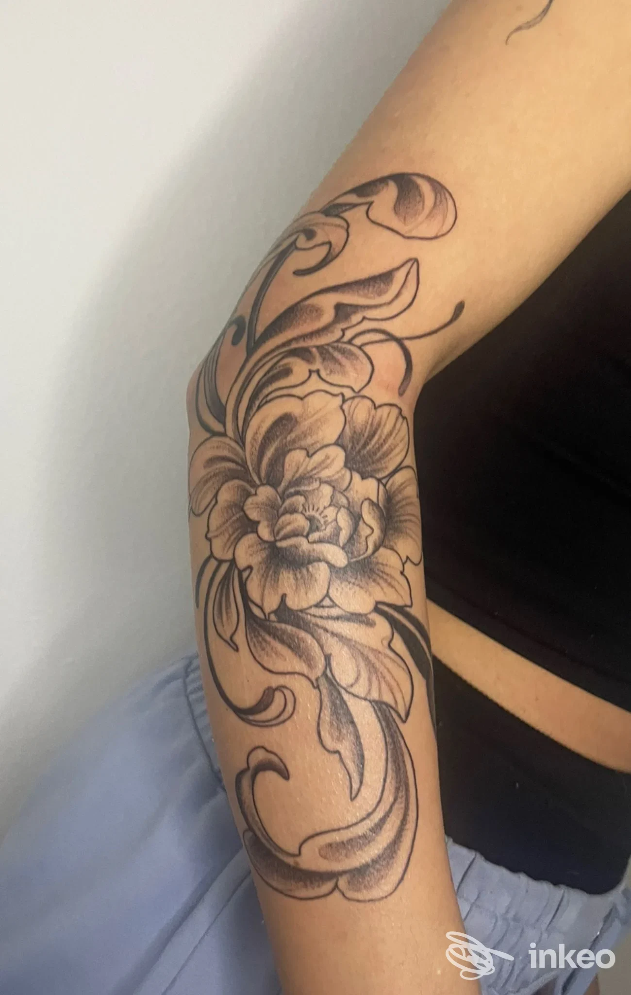 Tattoo floreale realizzato sulla pelle sul braccio di una persona, ritratto in primo piano senza viso visibile.