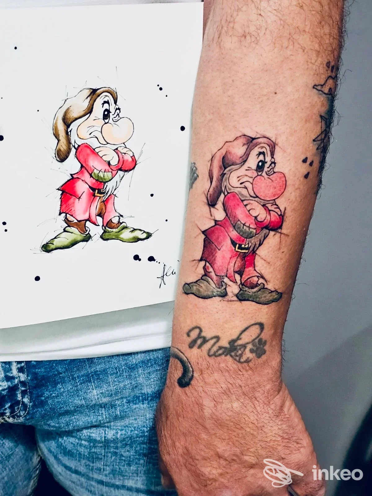 Tattoo a colori su avambraccio raffigurante un personaggio dei cartoni animati, con abbigliamento rosso e verde, eseguito su pelle reale.