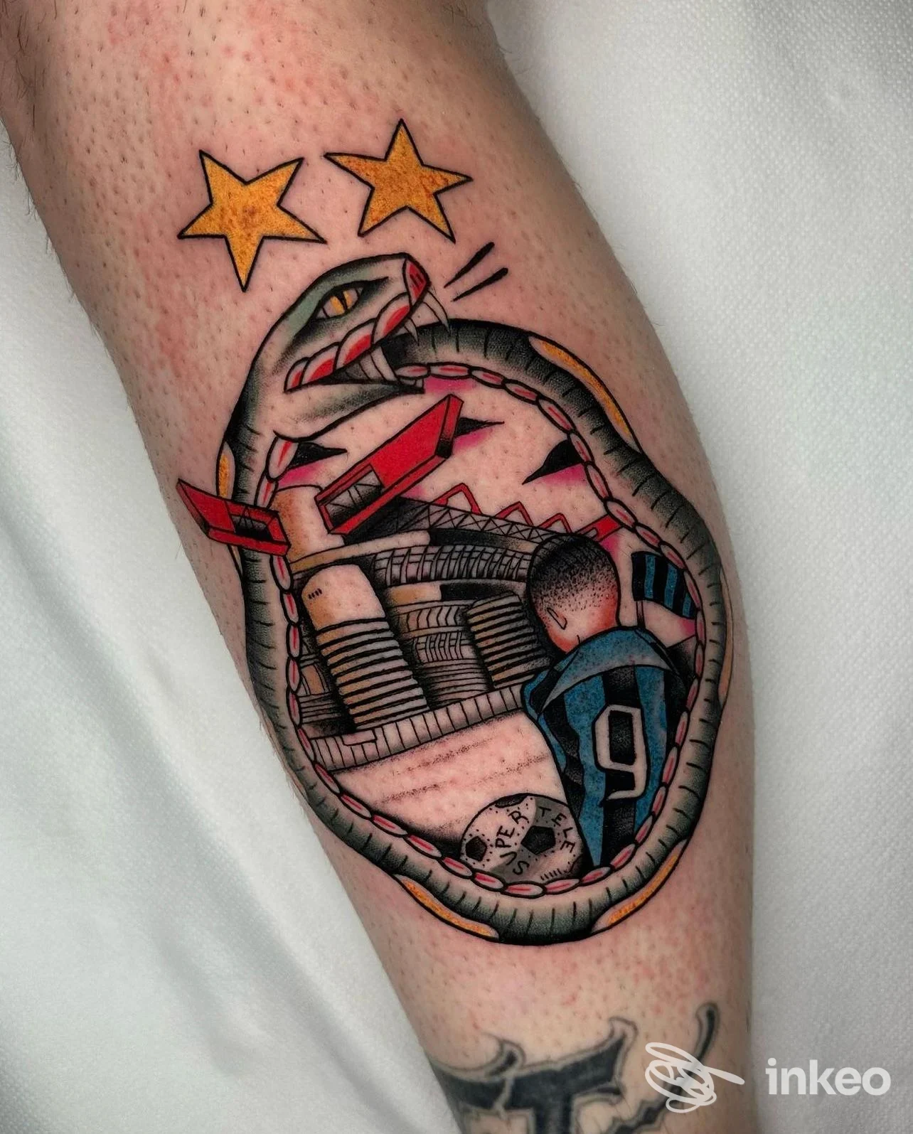 Tattoo a colori sull’avambraccio raffigurante una scena con una figura sportiva all’interno di una cornice circolare, accompagnata da due stelle gialle in alto.