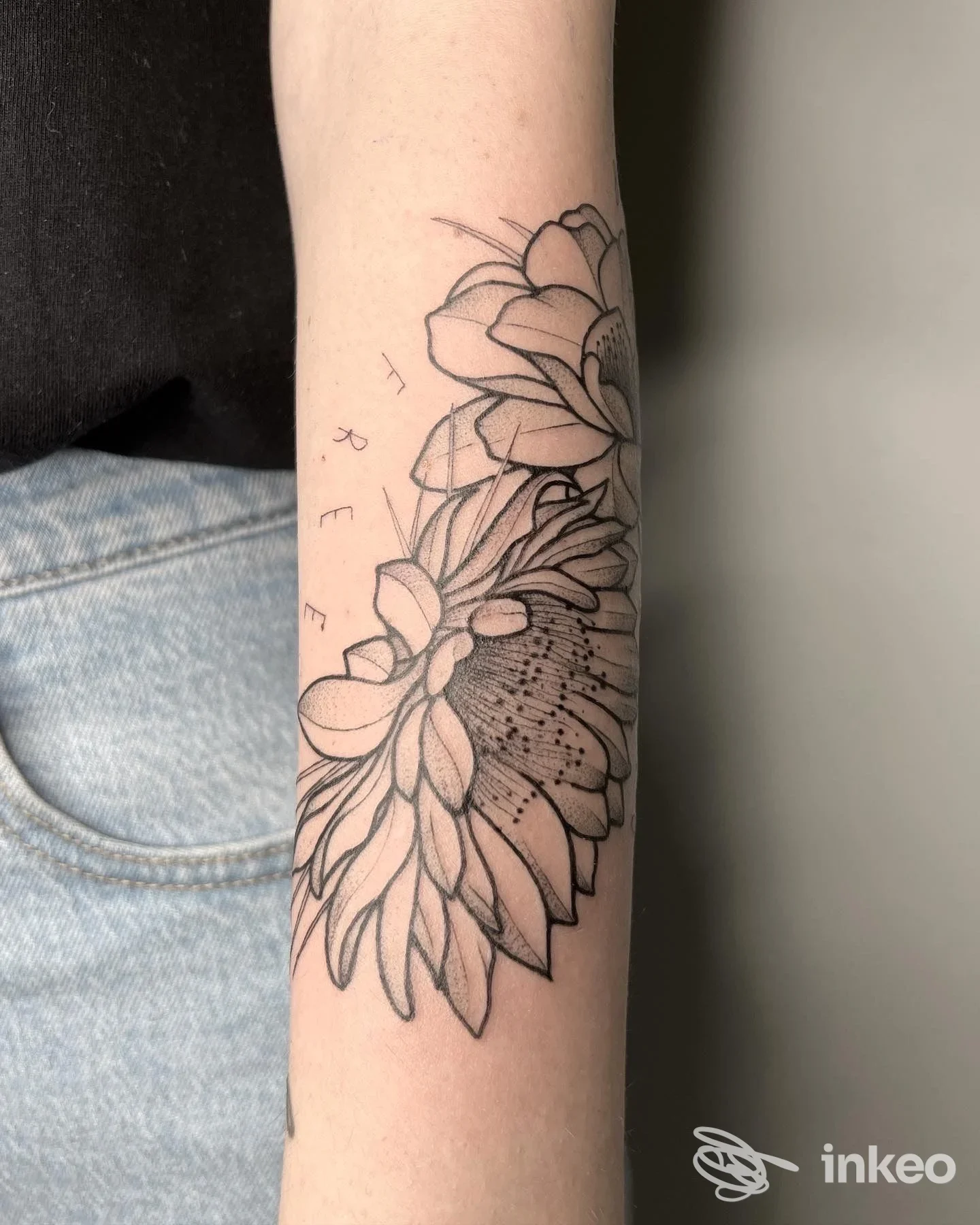 Tattoo lineare di fiori disegnati sul braccio, contorni neri su pelle chiara, senza volto visibile.