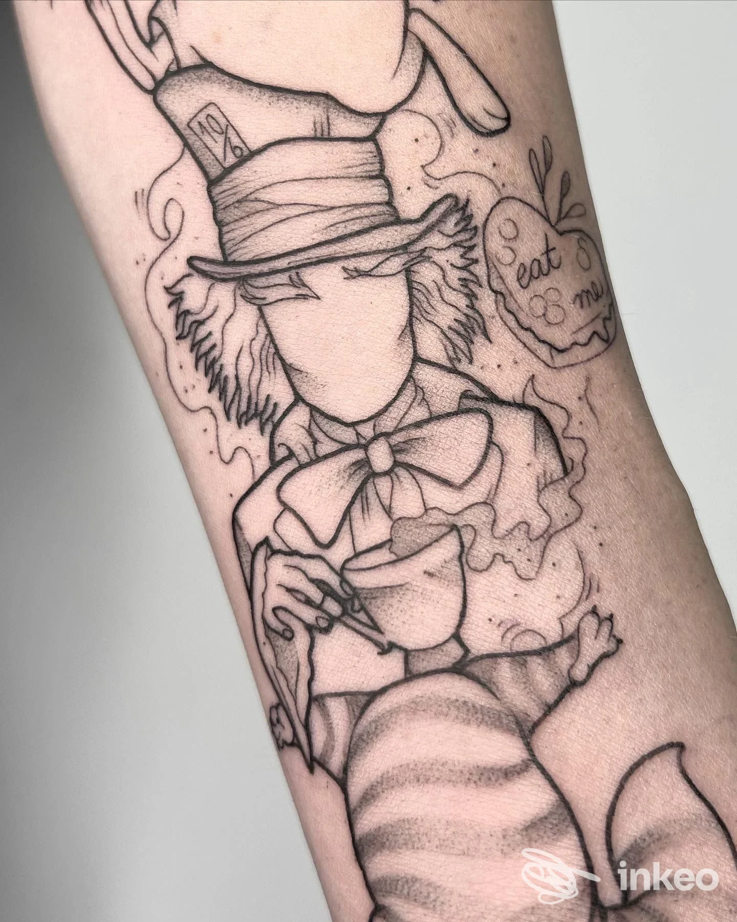 Tattoo su braccio raffigurante una figura in cappello e vestito, disegnata in stile schematico con contorni neri; visibile solo il corpo della persona, senza volto, in primo piano.