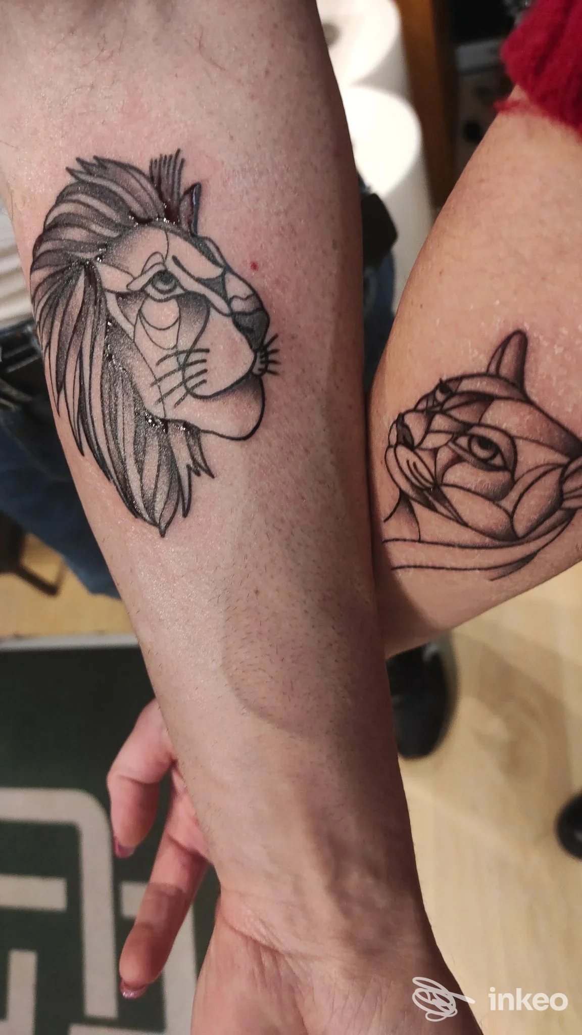 Due tatuaggi visibili su entrambi gli avambracci: leone stilizzato sul braccio sinistro e rosa su quello destro, in inchiostro nero.
