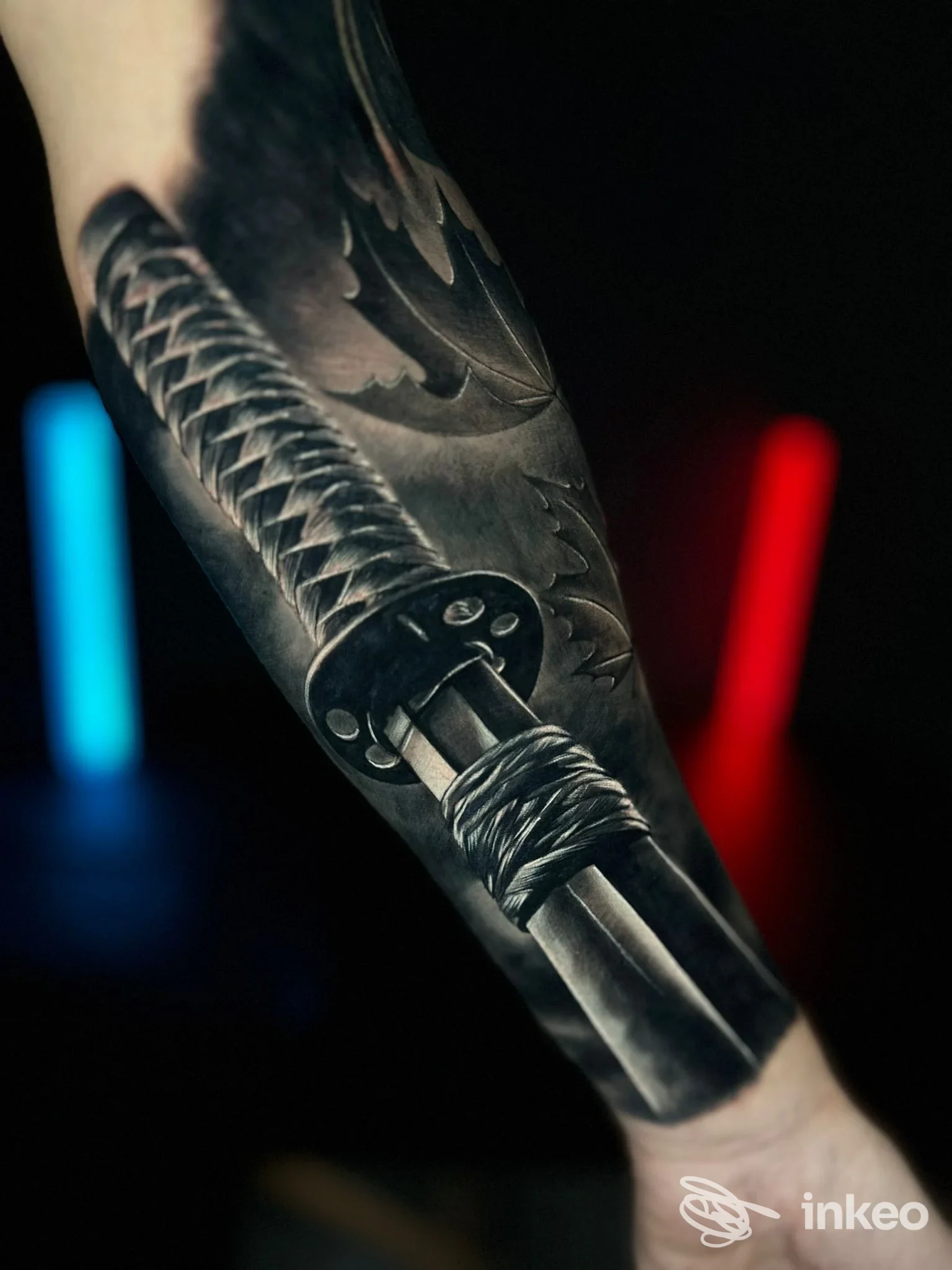 Tatuaggio realistico su avambraccio raffigurante una spada avvolta in corde, visibile su pelle nera; nessun volto visibile, luce morbida e sfondo scuro.