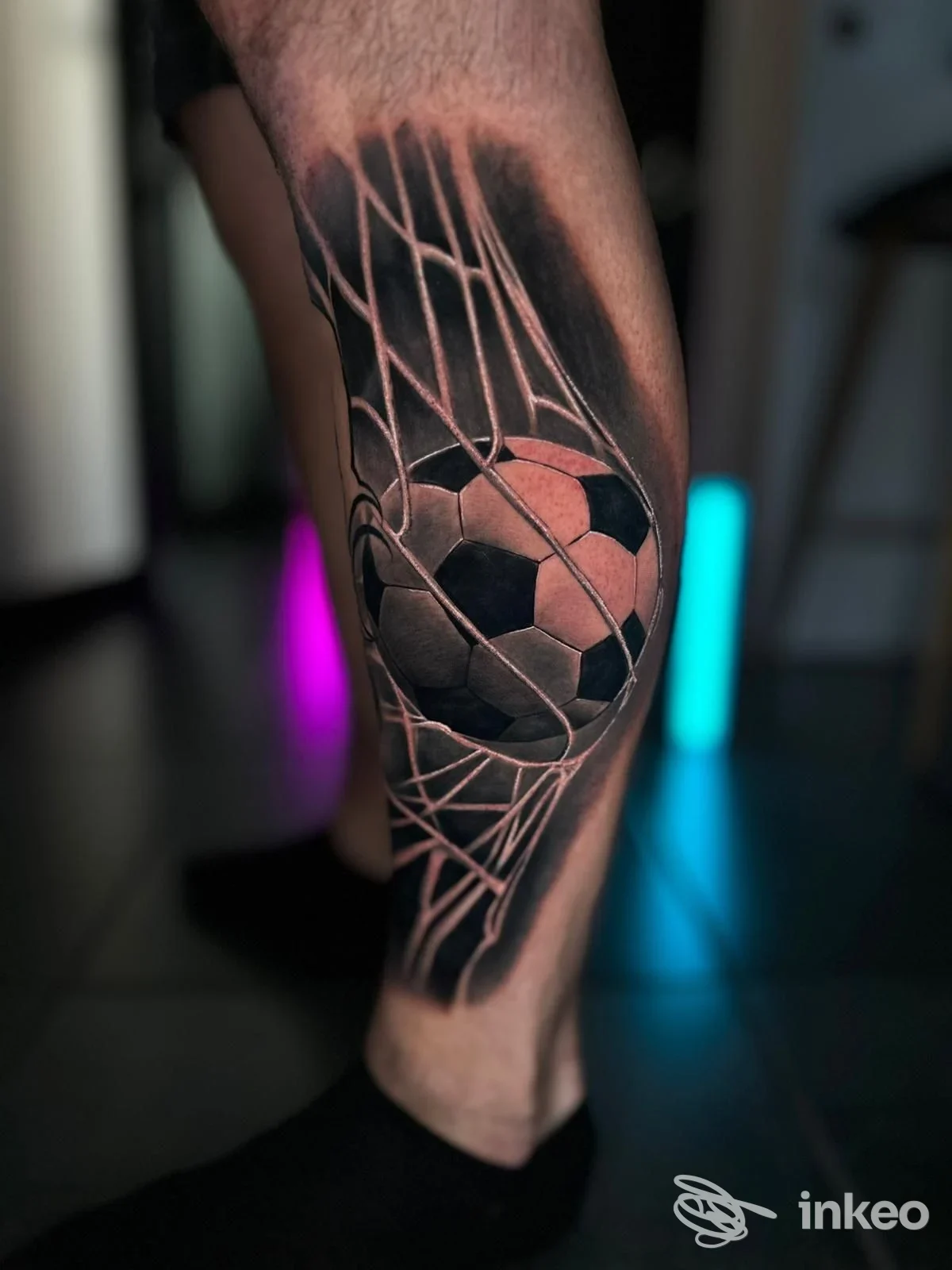 Tattoo sul polpaccio raffigurante un pallone da calcio con una rete geometrica.