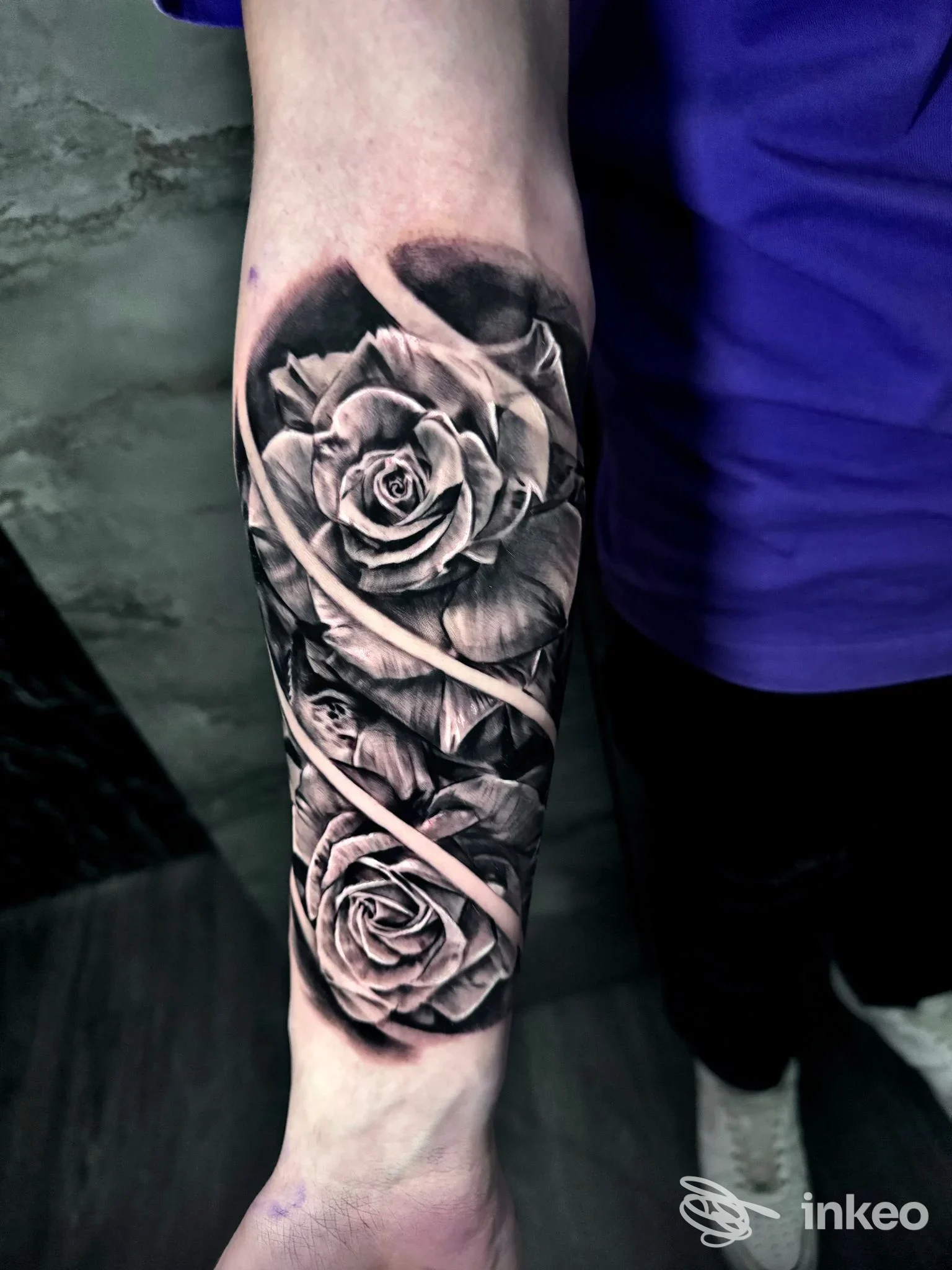 Avambraccio visibile con tatuaggio realistico in bianco e nero di due rose sovrapposte, lungo la parte anteriore dell’avambraccio, su pelle chiara. Senza volto visibile e senza elementi di social media.