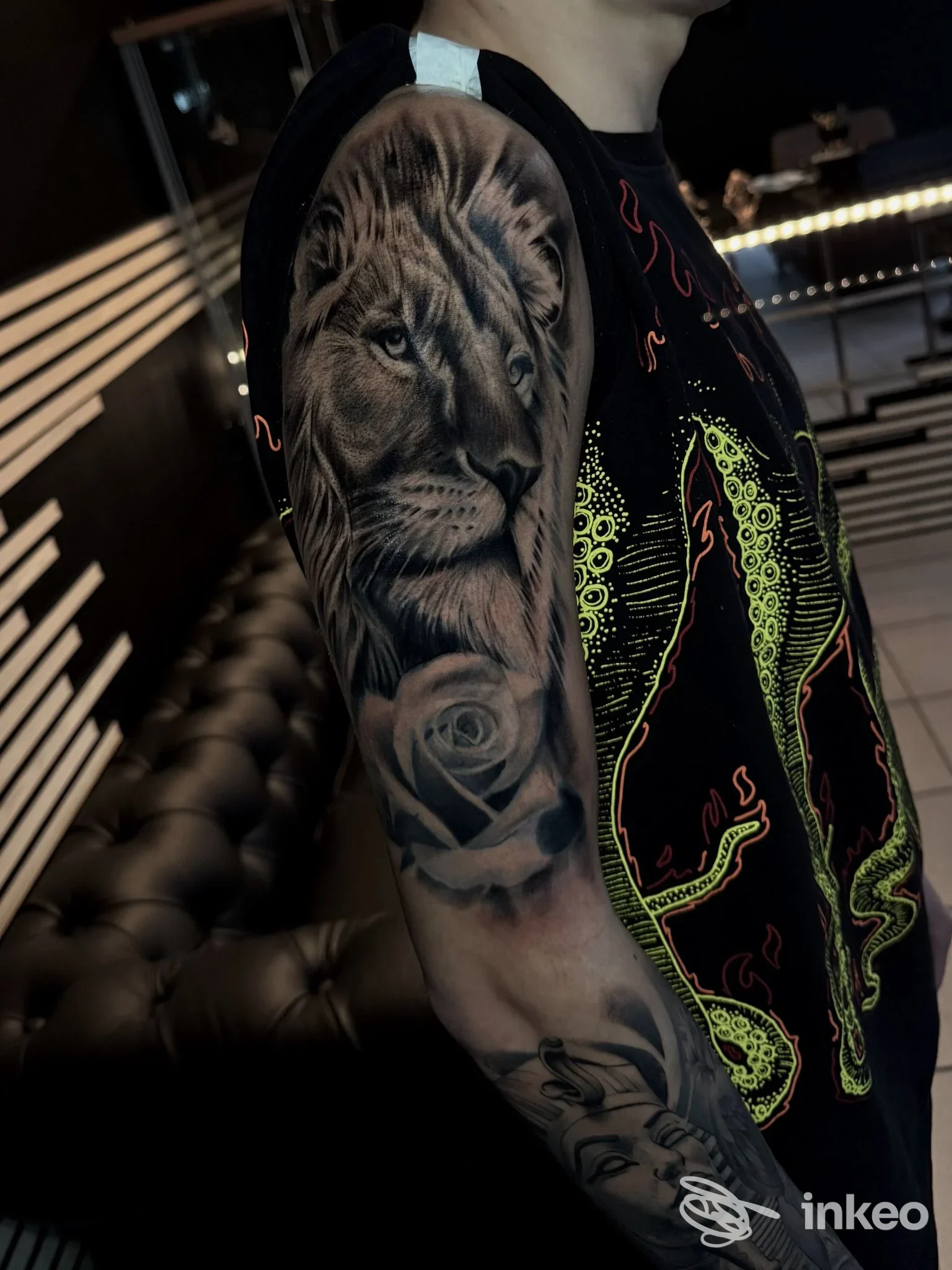 Tatuaggio realistico di un leone sull'avambraccio di una persona, visibile solo una porzione di braccio con tatuaggio in tonalità grigio/nerastre.