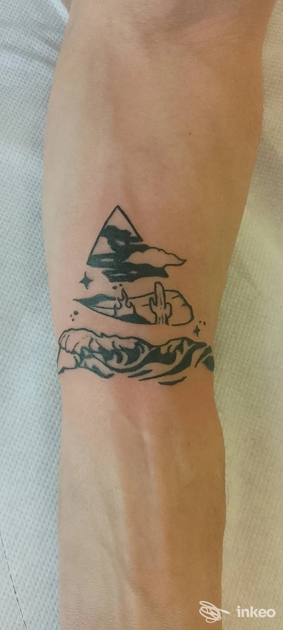 Tatuaggio realistico sull’avambraccio raffigurante un triangolo con paesaggio e mare, linee scure su pelle reale, eseguito dal studio CLOTATTOO.