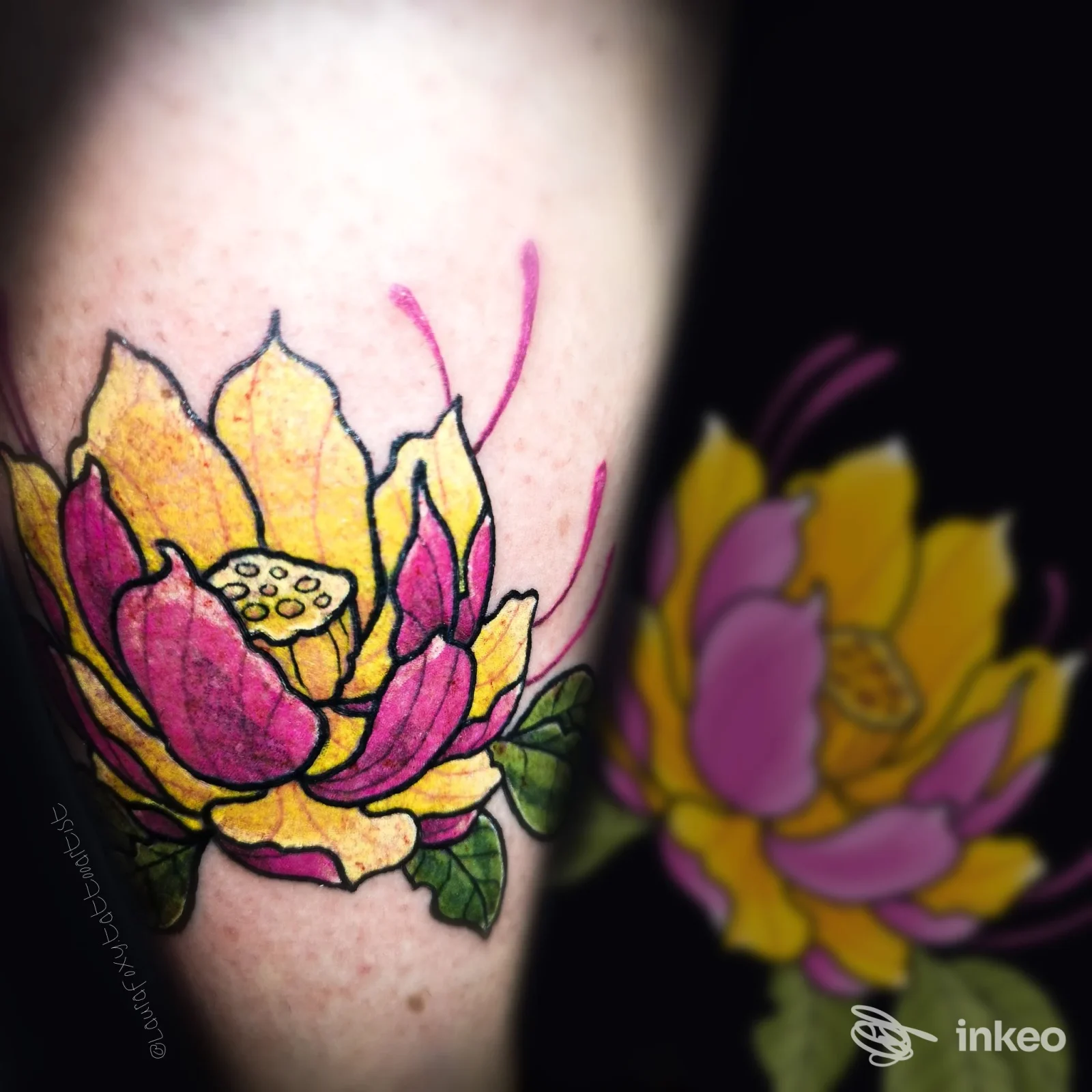 Tattoo colorato di lotus su pelle, sul braccio, con linee nere nette e colori giallo e magenta; si vede una seconda immagine riflessa sullo sfondo.