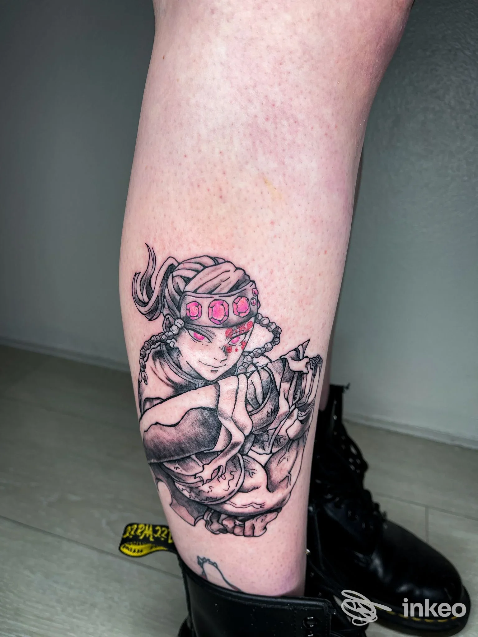 Tattoo visibile su pelle raffigurante una figura femminile con cerchietto rosa, su polpaccio; disegno in bianco e nero con tocchi di rosa, senza testo o watermark.
