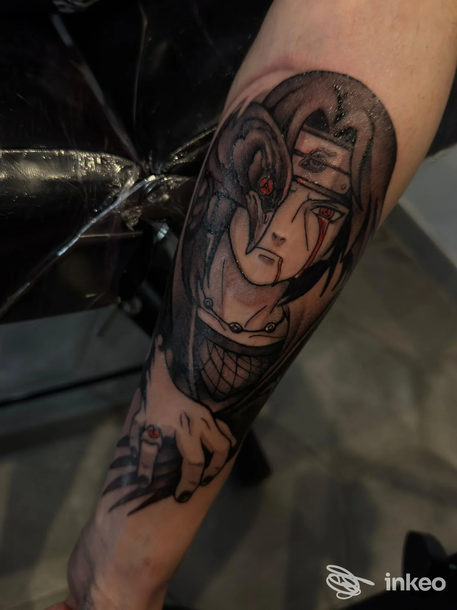 Tattoo visibile sull'avambraccio raffigurante una figura femminile disegnata, con dettagli scuri e accenti rossi agli occhi, realizzato su pelle reale.