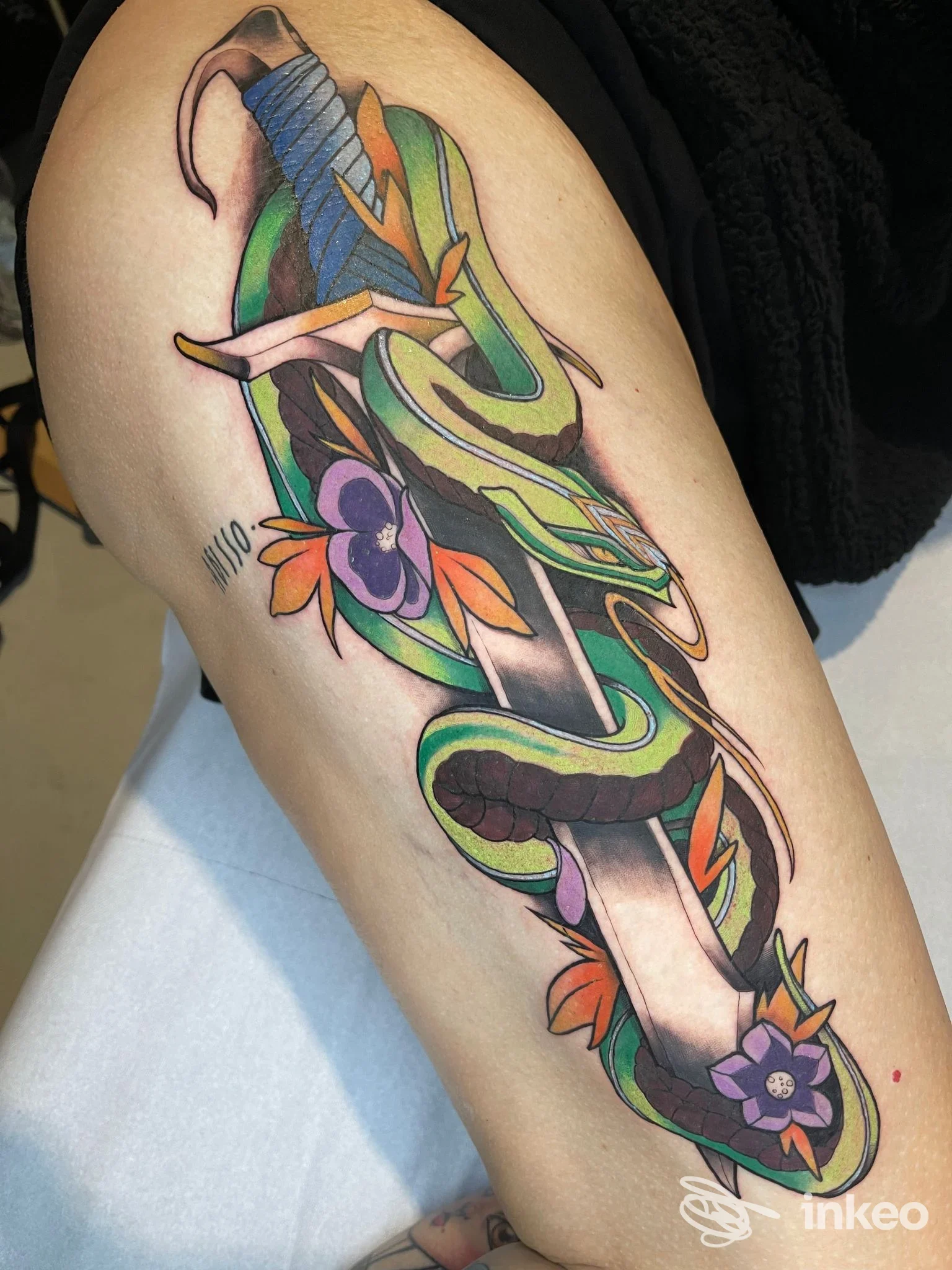 Tattoo colorato e dettagliato su braccio nudo, disegno floreale e decorativo con linee e sfumature vivaci, visibile su pelle reale presso lo studio Il Kamaleonte Tattoo Studio.