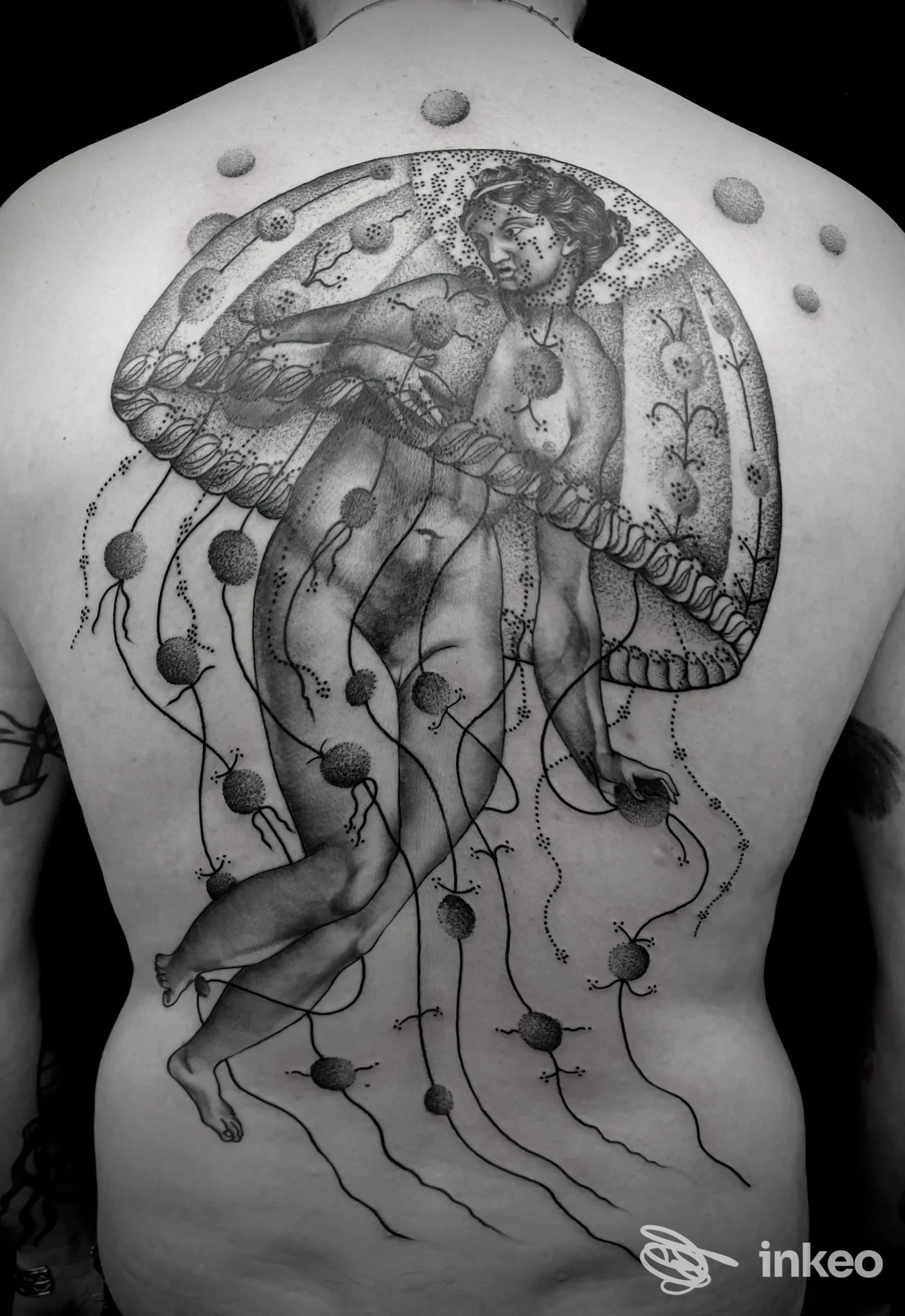 Schiena di una persona con un grande tattoo in bianco e nero raffigurante una figura umana racchiusa in una cupola, con tentacoli che scendono lungo la schiena, senza testo né watermark.