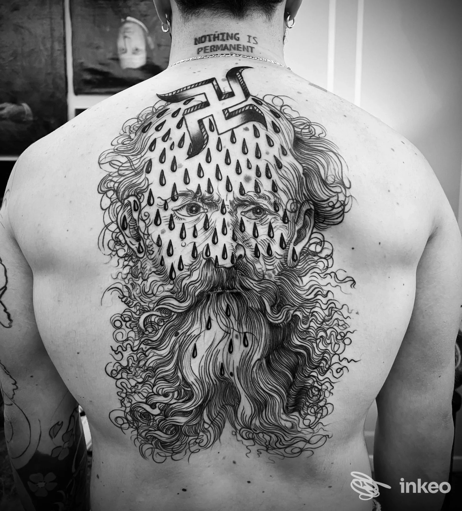 Tattoo sul dorso raffigurante un volto barbuto con gocce scure che scendono dall’alto della testa, coprendo gran parte della schiena, in bianco e nero.