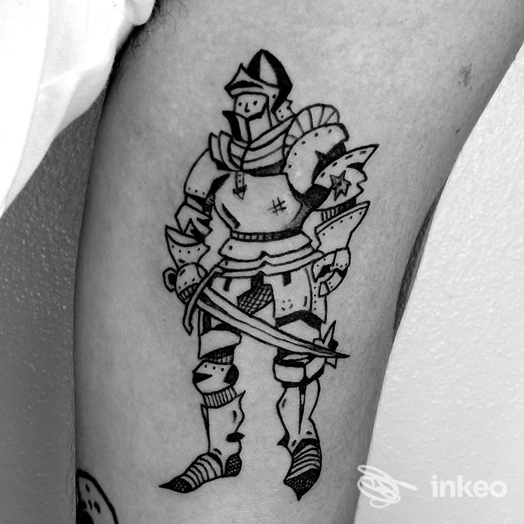 Tattoo in stile armatura su pelle: guerriero in armatura, disegnato con linee nere sul braccio di una persona, senza testo né overlay sociale.