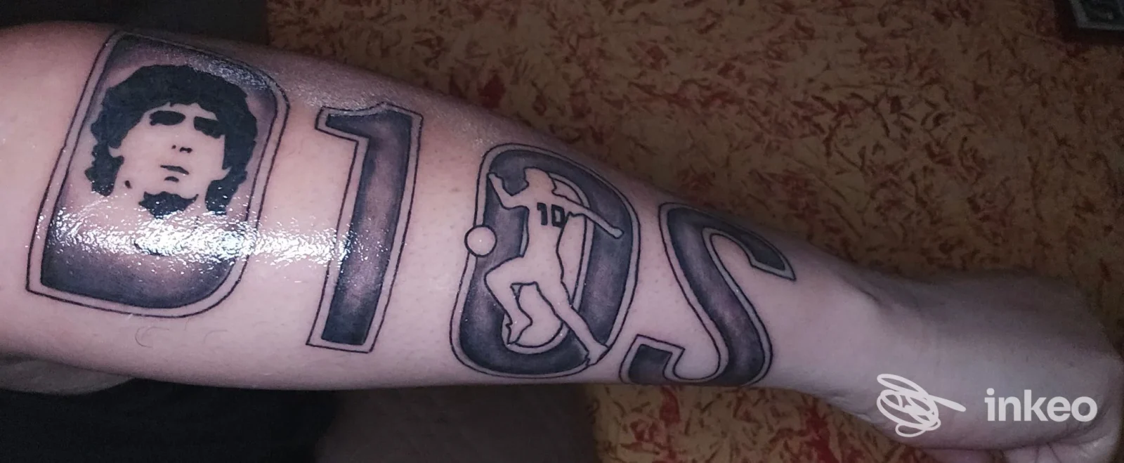 Avambraccio con tatuaggio a blocchi: ritratto in un rettangolo, simboli e lettere contiguous, eseguito in stile inchiostrato; lavoro su pelle visibile presso Pit Bull Tattoo, Cura Carpignano.