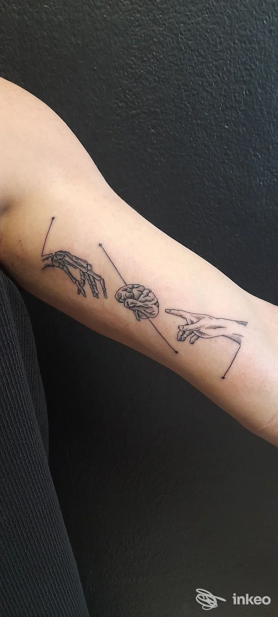 Braccio di una persona con un tatuaggio visibile: due mani stilizzate e una mancanza di contorno chiaro su sfondo neutro, stile disegno lineare.