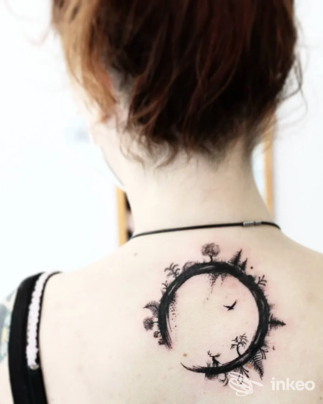 Tattoo nero sul retro del collo raffigurante un cerchio aperto con palme e uccelli, realizzato sulla pelle. Studio Orsotatù, città non specificata.