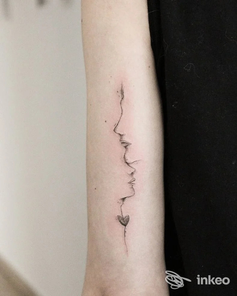 Avambraccio fotografo mostra un tatuaggio a linea continua che disegna profili di volti allineati lungo la pelle, tratteggio leggero e dettagliano delicatamente l’avambraccio.