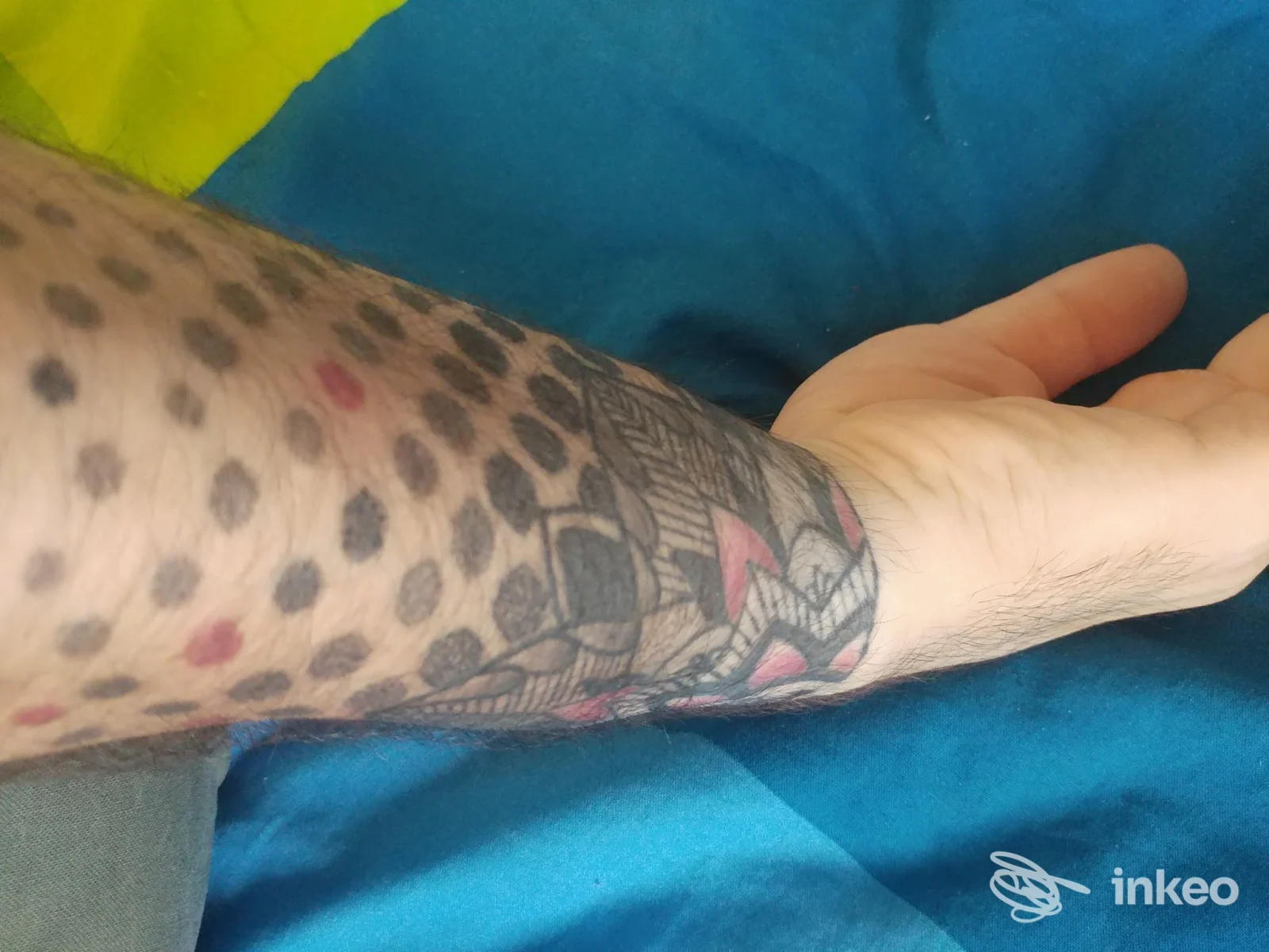 Avambraccio sinistro con tattoo leopardato e motivo decorativo sul polso, tratto pulito con contorni neri e riflessi di colore su sfondo blu. Milano, Tabatattoo.
