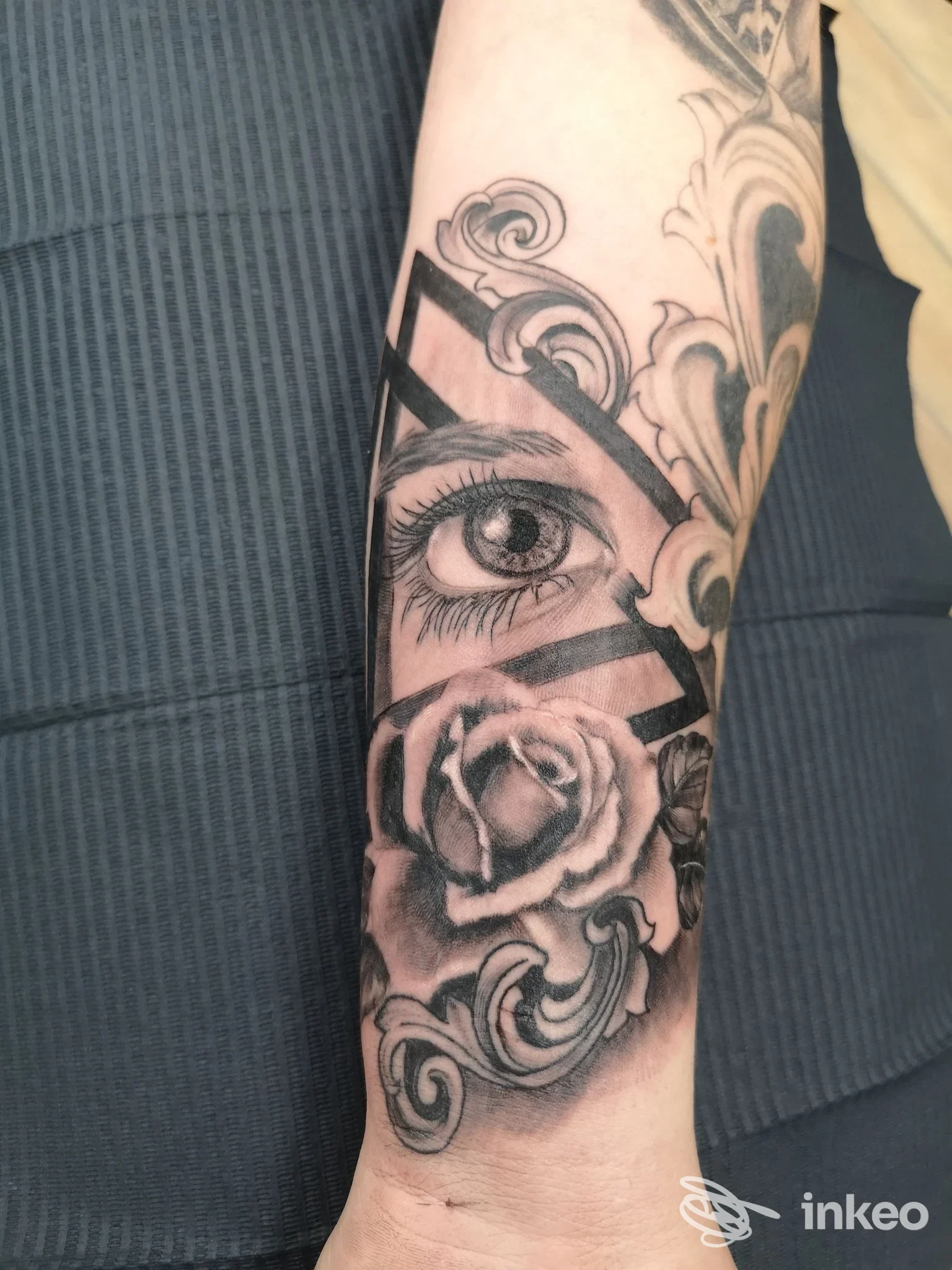 Tattoo visibile sull’avambraccio: rosa realistica al centro con motivi ornamentali e linee nere geometriche, sul supporto pelle.