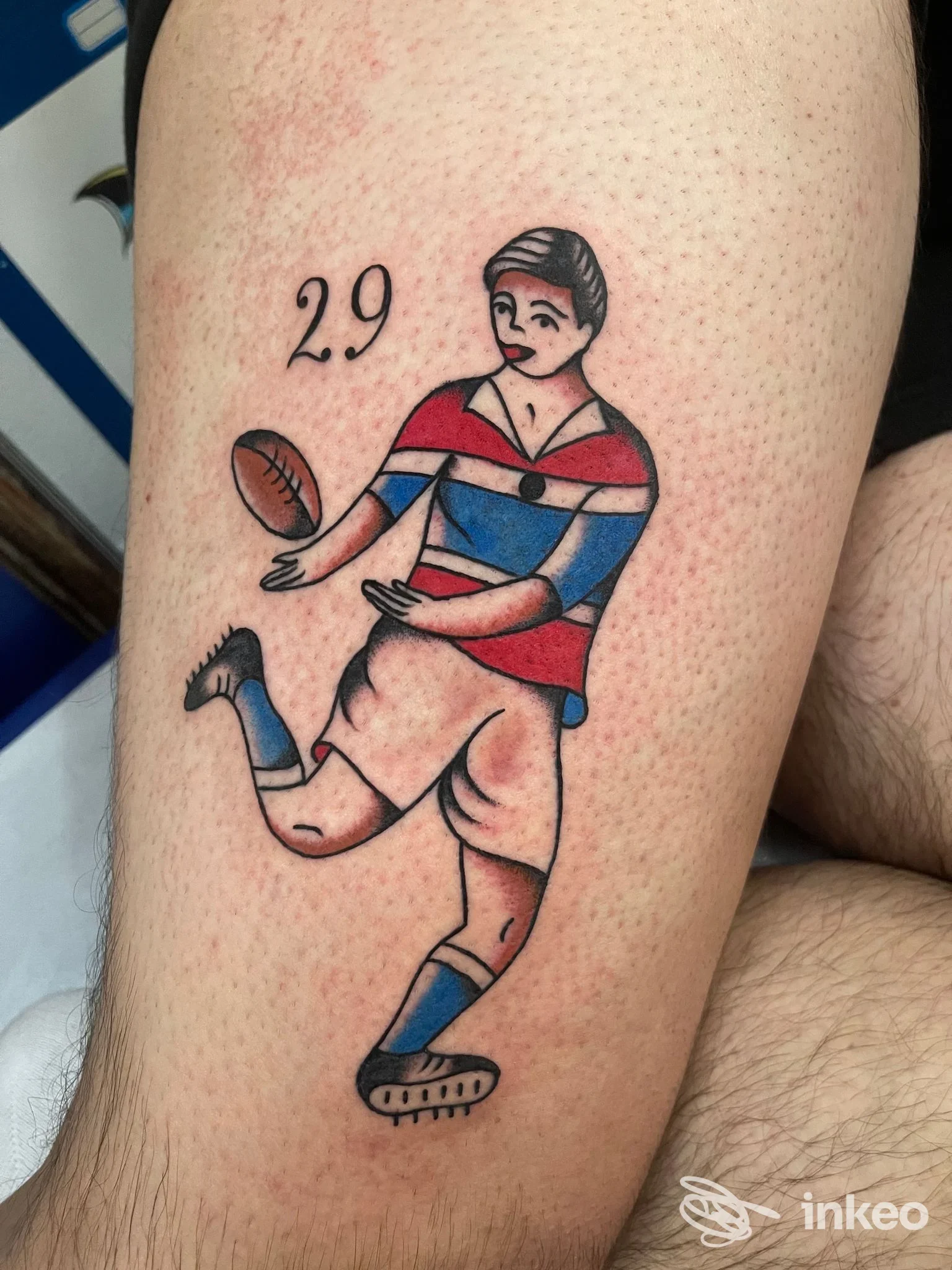 Tattoo colorato di un giocatore di calcio stilizzato sulla pelle della gamba, visibile in primo piano senza volto umano.