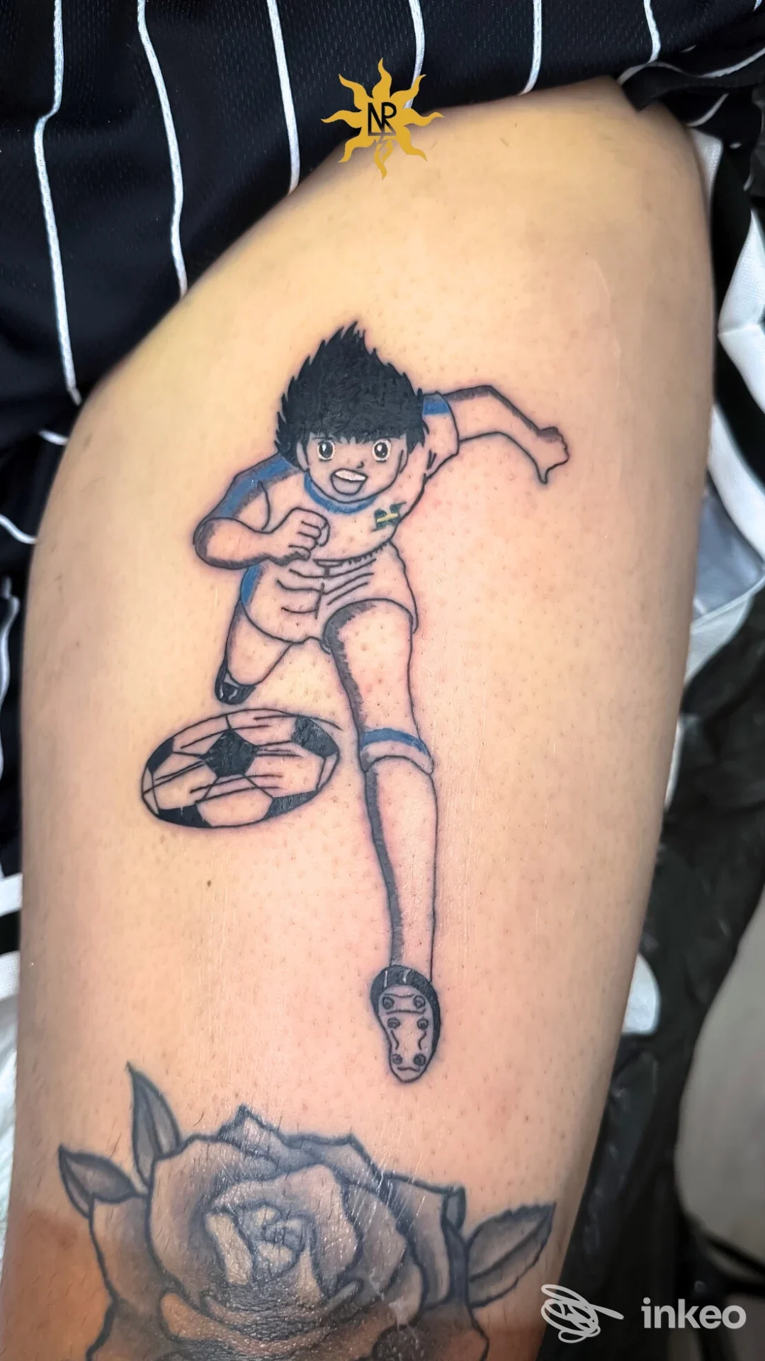 Tattoo su gamba raffigurante un ragazzo che corre, con una scarpa, accompagnato da una grande rosa in basso; stile cartoon.