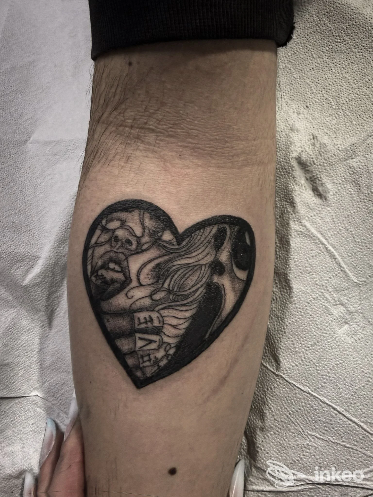Tattoo sul braccio a forma di cuore, in bianco e nero, con dettagli scuri e contorni definiti.