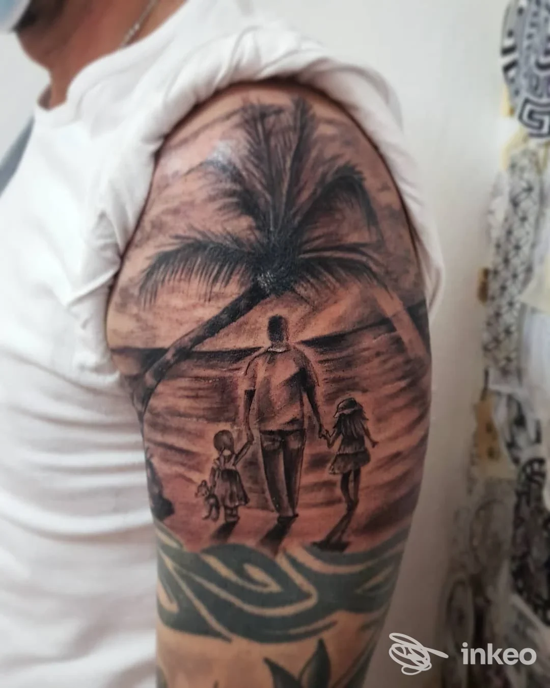 Tatuaggio realistico sull'avambraccio raffigurante una scena di spiaggia al tramonto con palma, un uomo e due bambini che camminano lungo la battigia.
