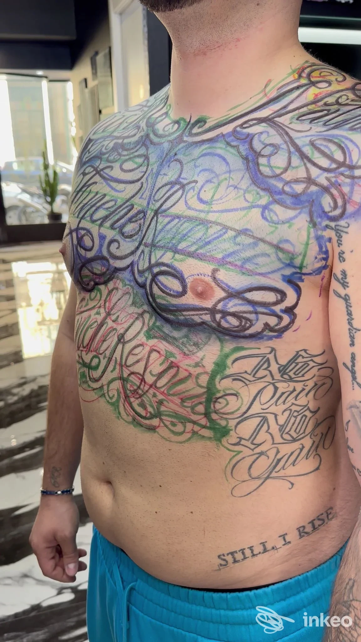 Torace e addome di un uomo tatuato, con braccia parzialmente visibili, tatuaggi colorati e intricati che coprono la pelle. Foto interna dello studio a Milano Tiburón Tattoo.