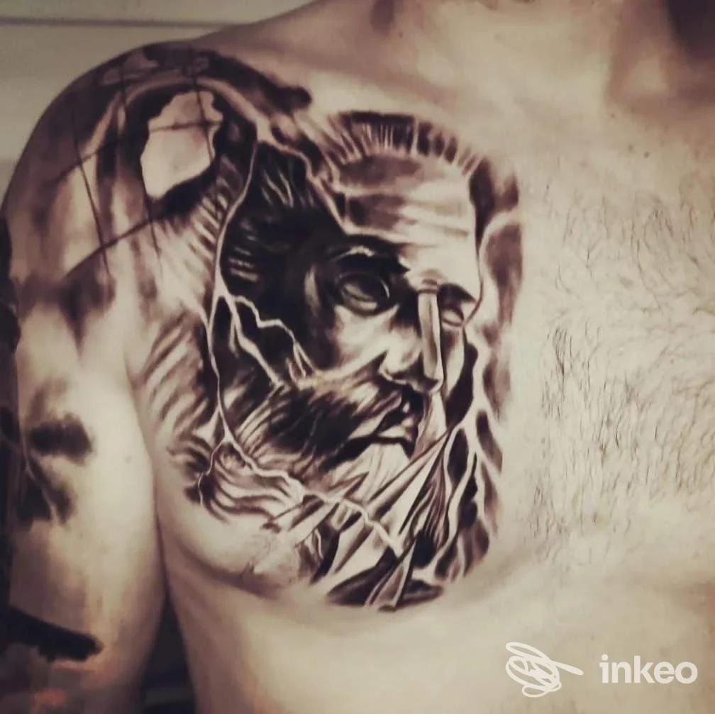 Tatuaggio in bianco e nero sul torace di un uomo, raffigurante una testa stilizzata con dettagli realistici, visibile sulla pelle.
