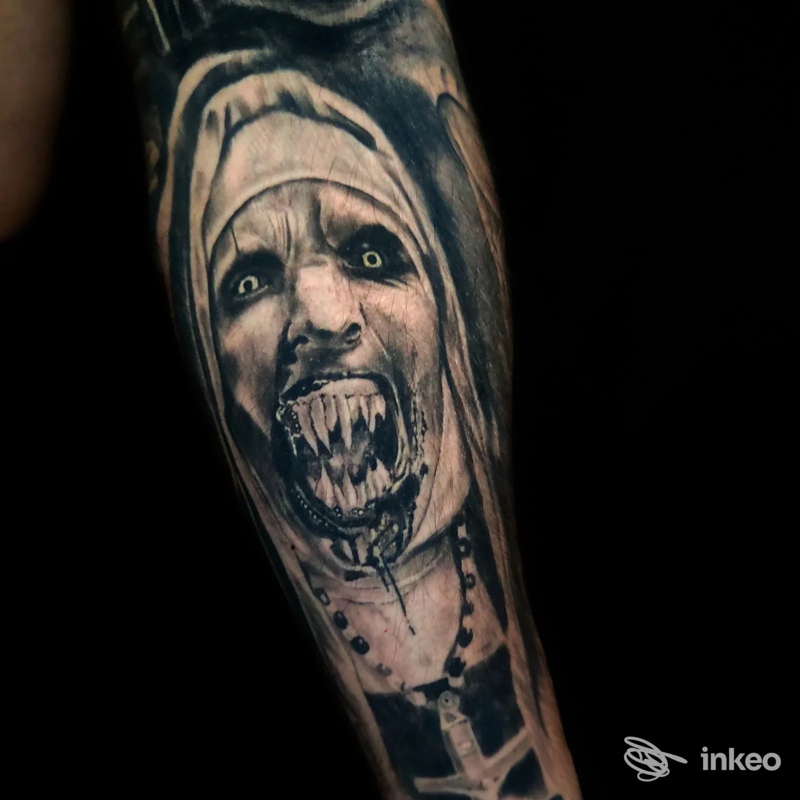 Dettaglio di braccio con tatuaggio realistico raffigurante una figura religiosa con espressione feroce, realizzato dallo White Ink Studio a Locate Varesino.