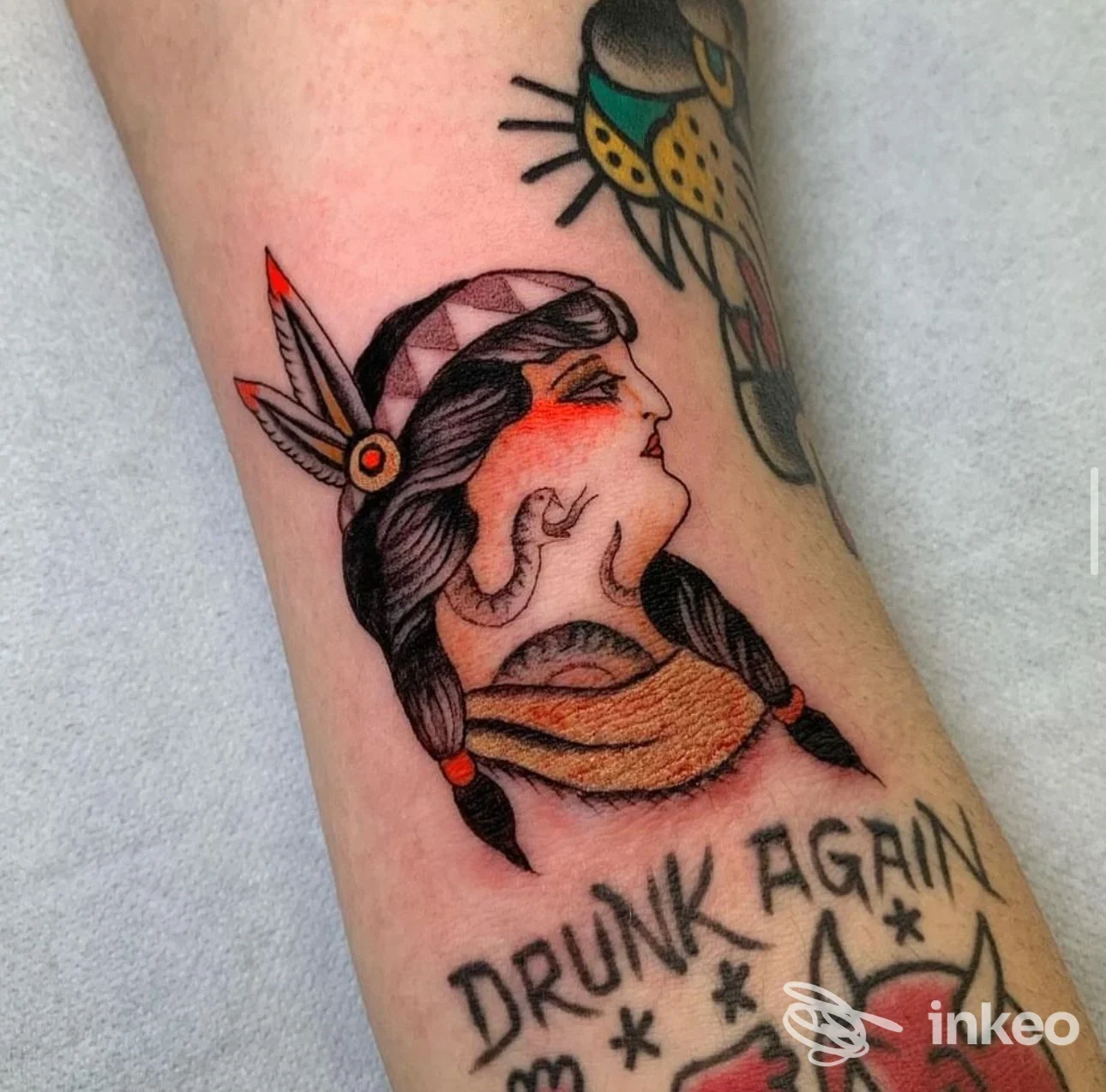 Tattoo visibile sul braccio raffigurante un profilo femminile con cappelli e sciarpa, linee marcate e colori sobri, stile tradizionale/neotradizionale; sullo sfondo si legge la scritta Drunk Again. Studio Rock Of Ages Tattoo, Seregno.
