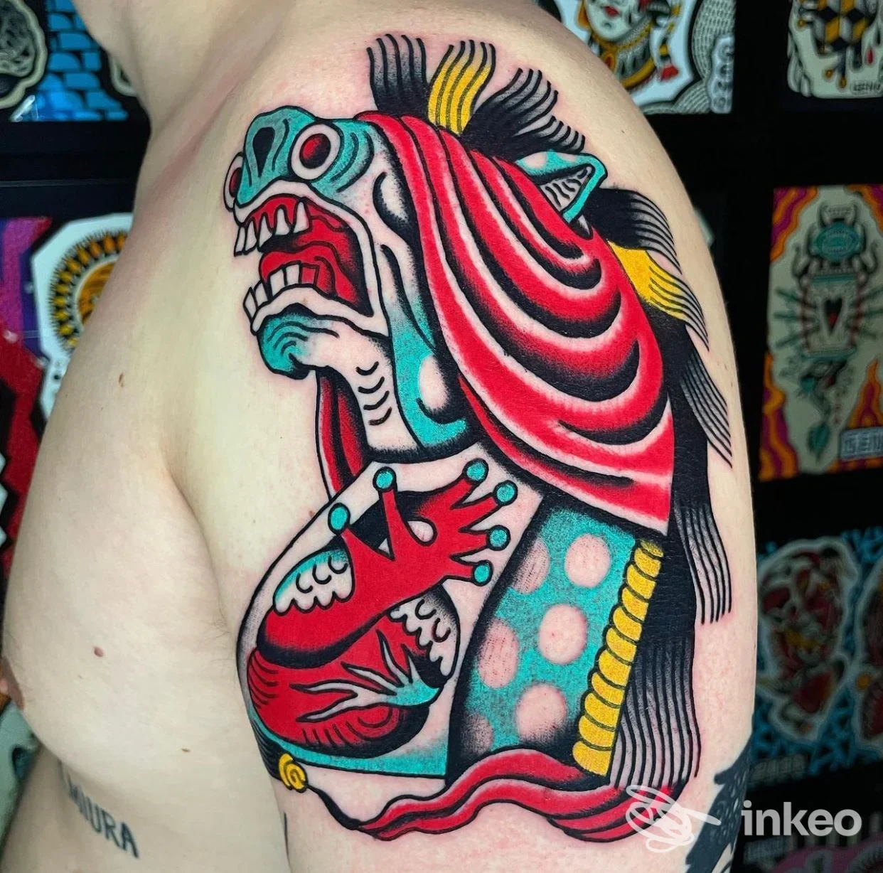 Tatuaggio a tema mostruoso colorato su braccio, disegno in stile old school con contorni netti e colori vivaci; si vede la pelle e i dettagli del tattoo su braccio sinistro.