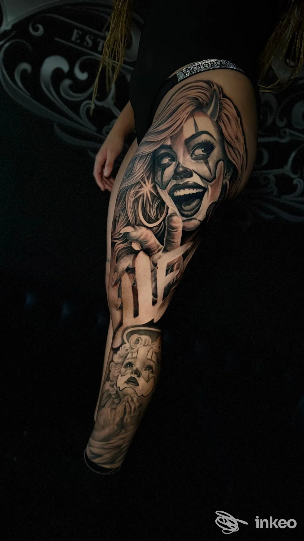 Tattoo realistico su gamba con ritratto di clown dettagliato, tonalità in bianco e nero e sfumature, visibile in profilo laterale.